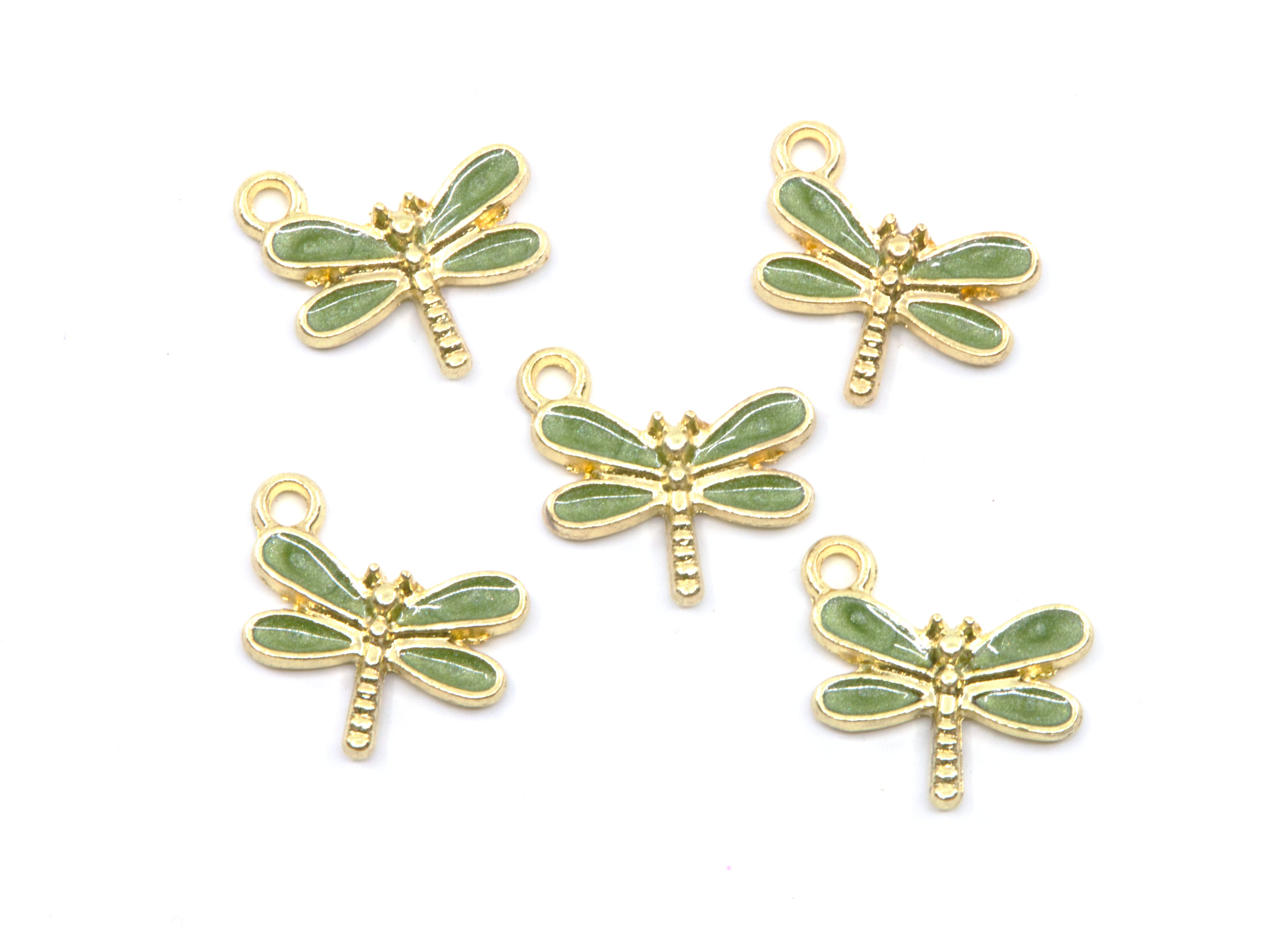 Five dragonfly-shaped jewelry charms with light green enamel wings and gold-tone metal bodies, arranged on a plain white background.