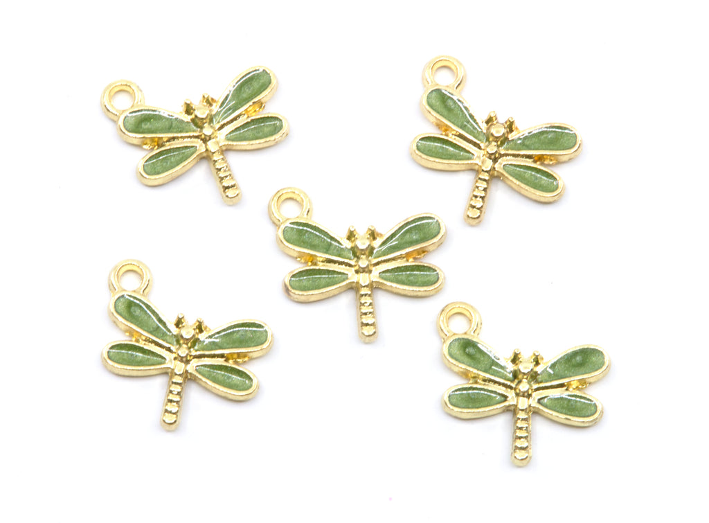 Five dragonfly-shaped jewelry charms with light green enamel wings and gold-tone metal bodies, arranged on a plain white background.