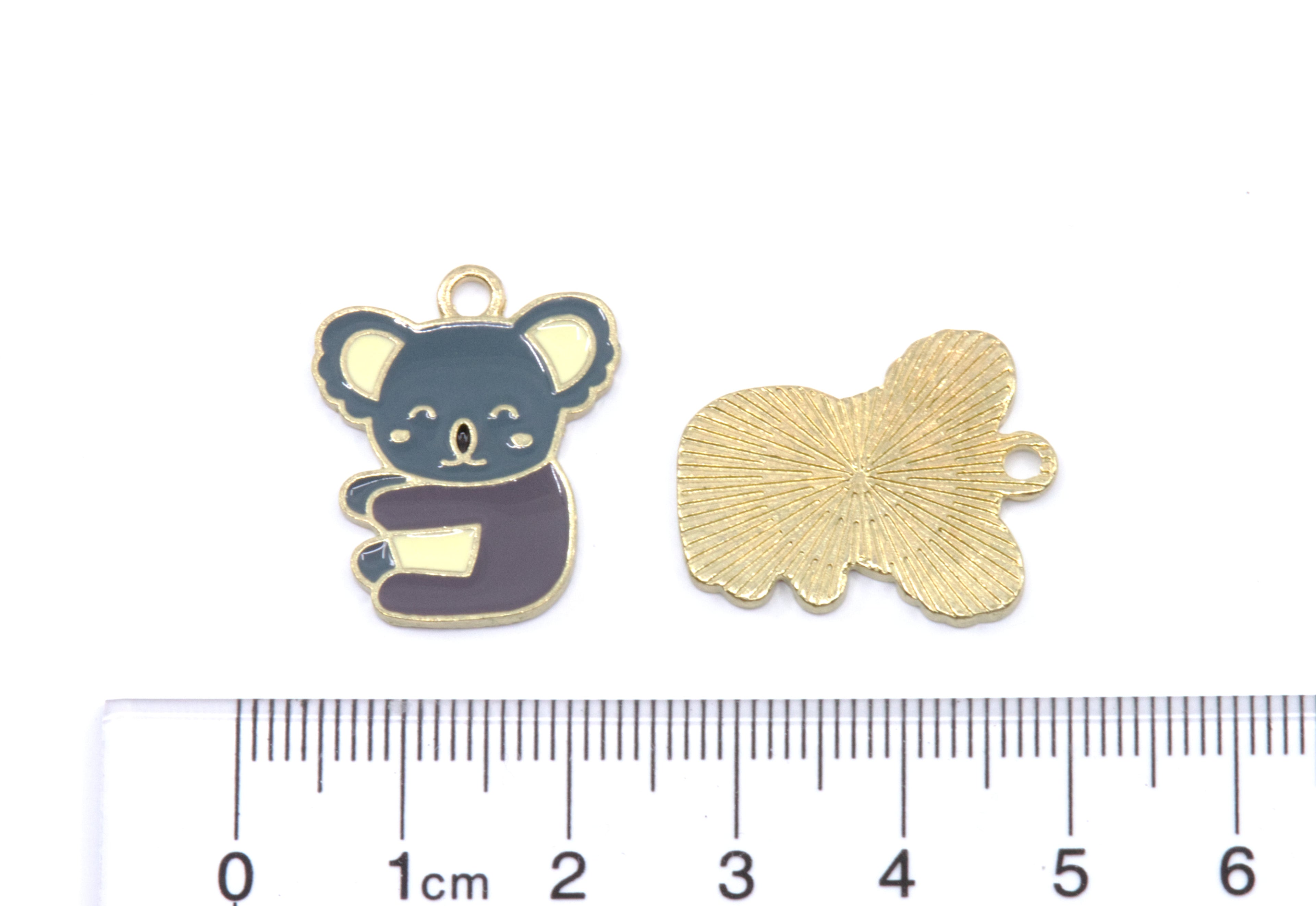 Two small koala-shaped charms shown on a white background with a cm ruler below for scale. 