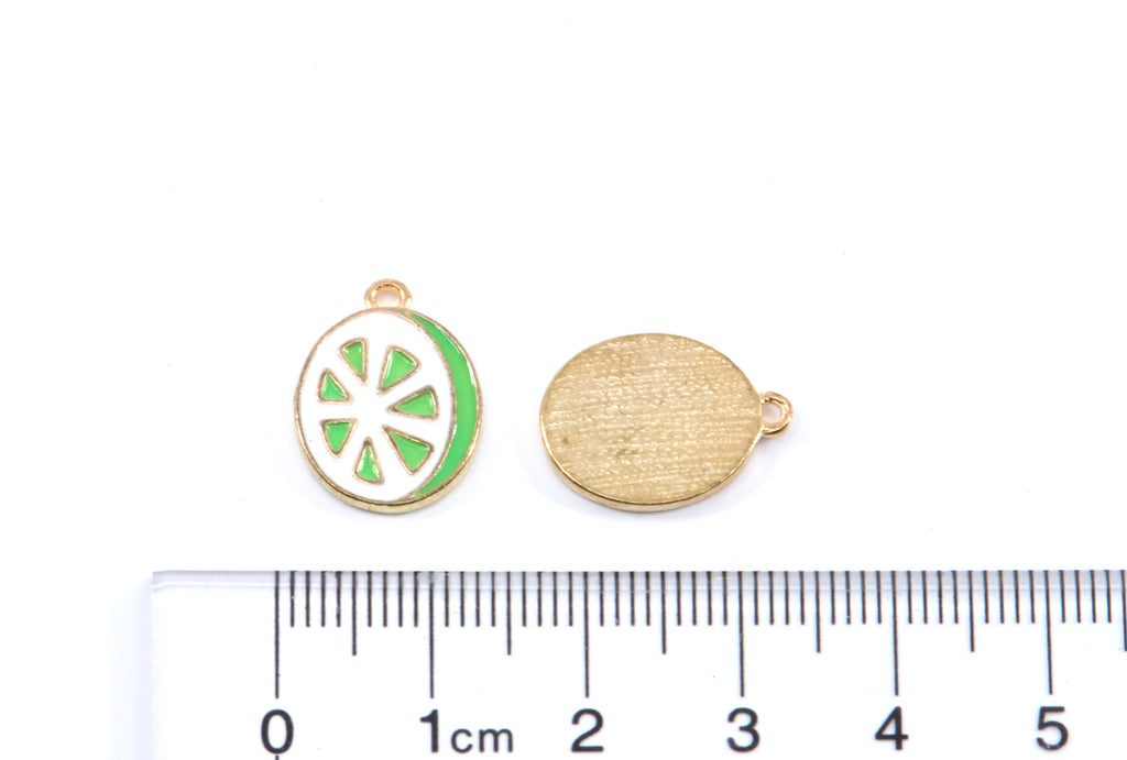 Two green and white lime slice charms on a white background with a  cm ruler below for scale. 