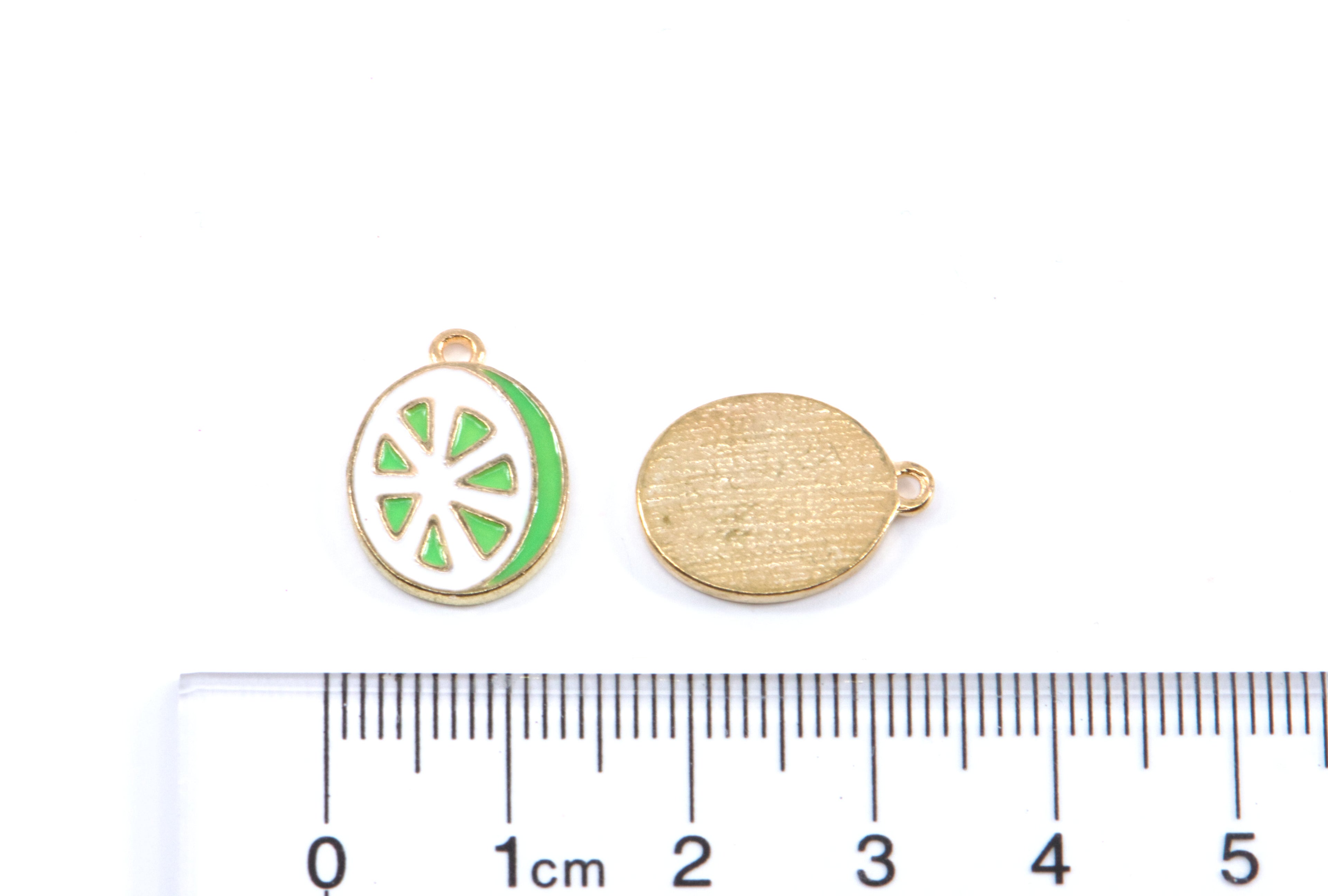 Two green and white lime slice charms on a white background with a  cm ruler below for scale. 