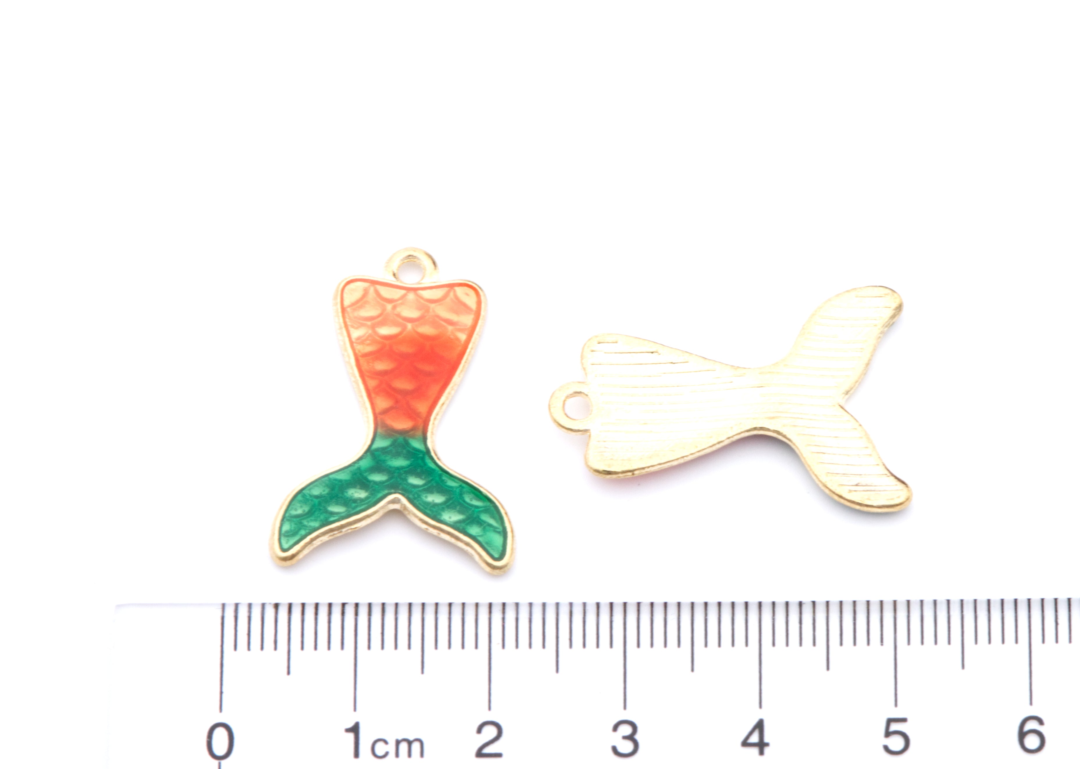 Two mermaid tail charms shown on a white background with a cm ruler below for scale. 