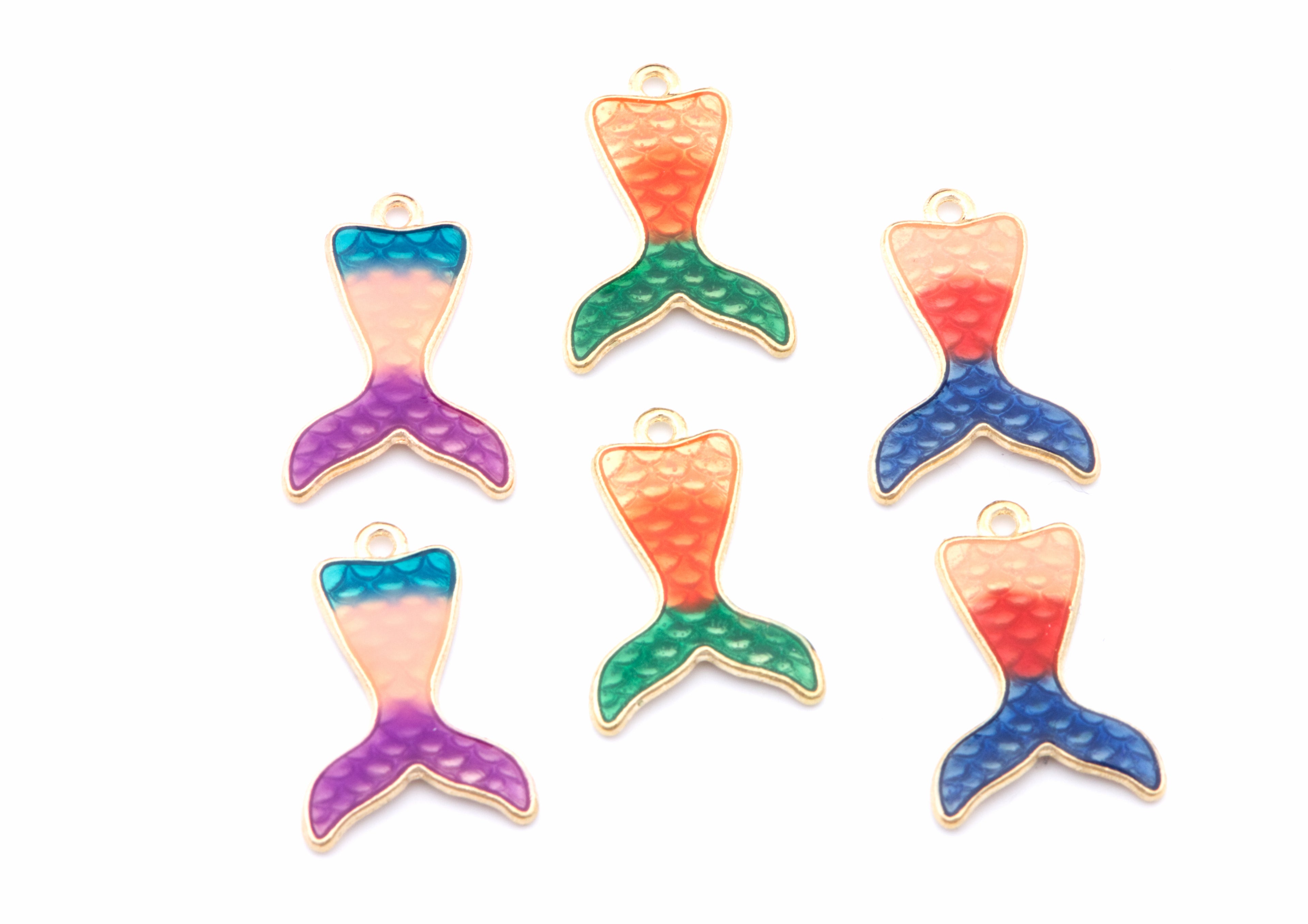 Six mermaid tail charms with a textured appearance enamel finish in various color combinations of blue, green, orange, pink, and purple, outlined in gold-tone metal, arranged on a plain white background.