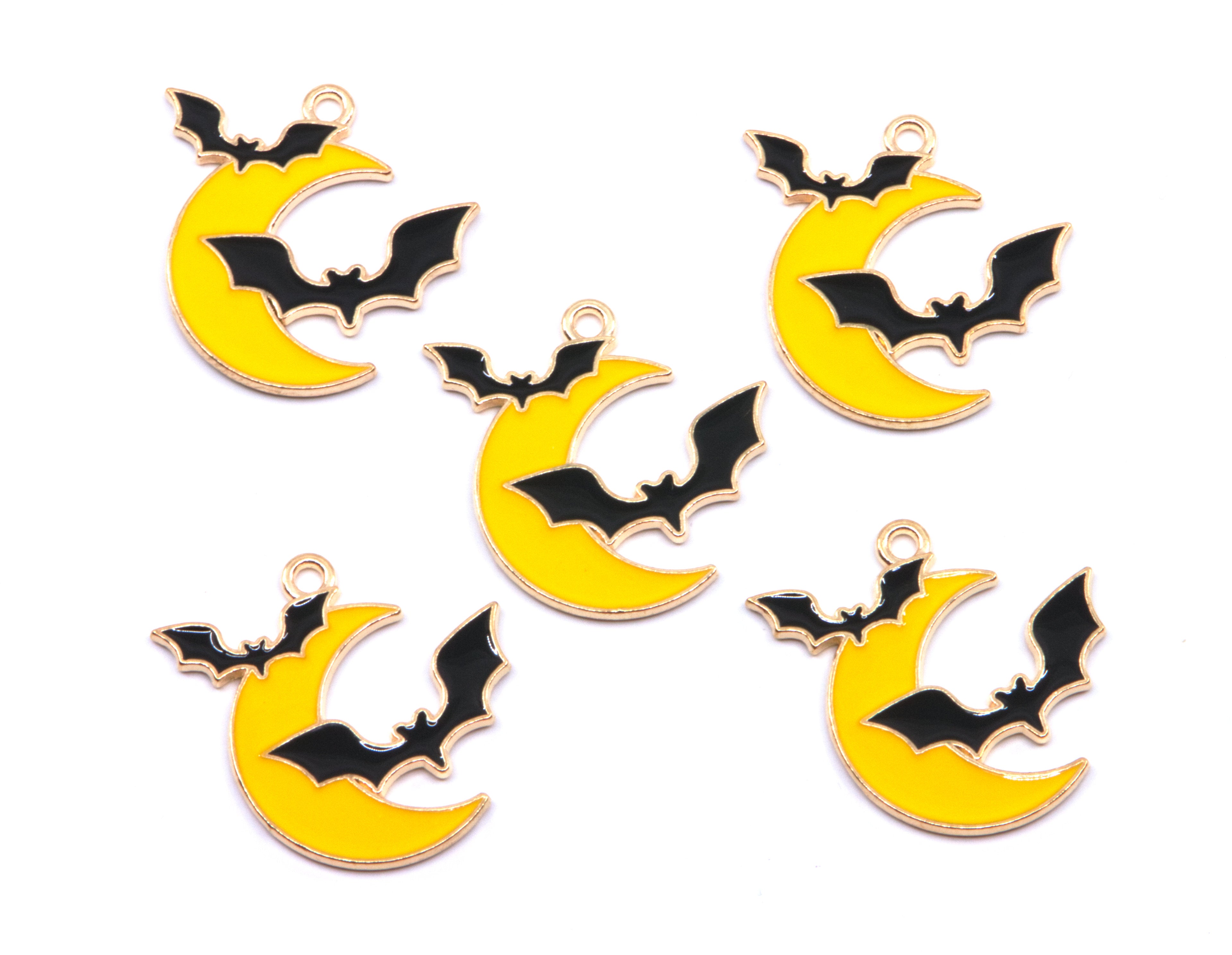 Five yellow crescent moon charms with black bat designs and gold-tone edges, arranged on a plain white background.