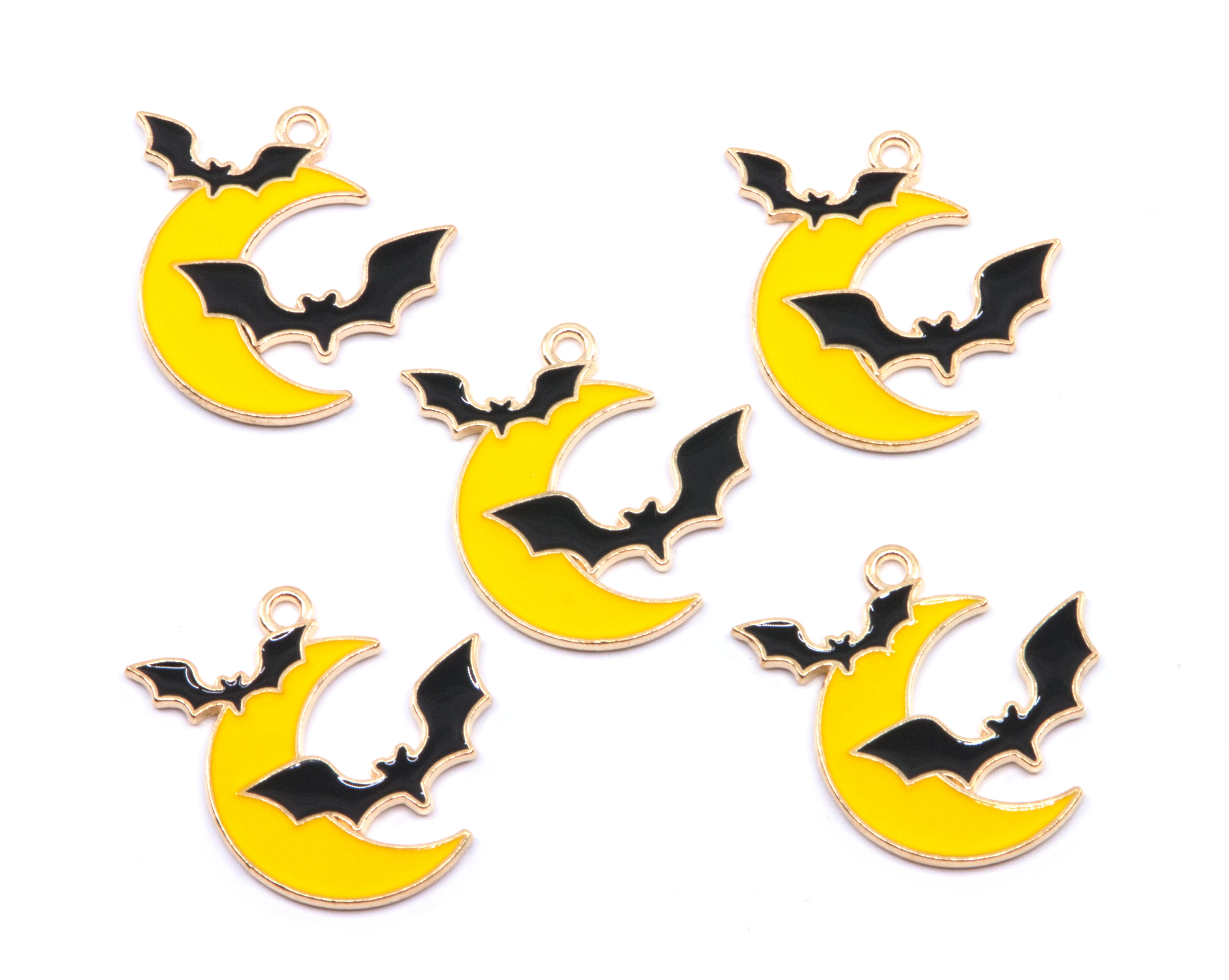 Five yellow crescent moon charms with black bat designs and gold-tone edges, arranged on a plain white background.