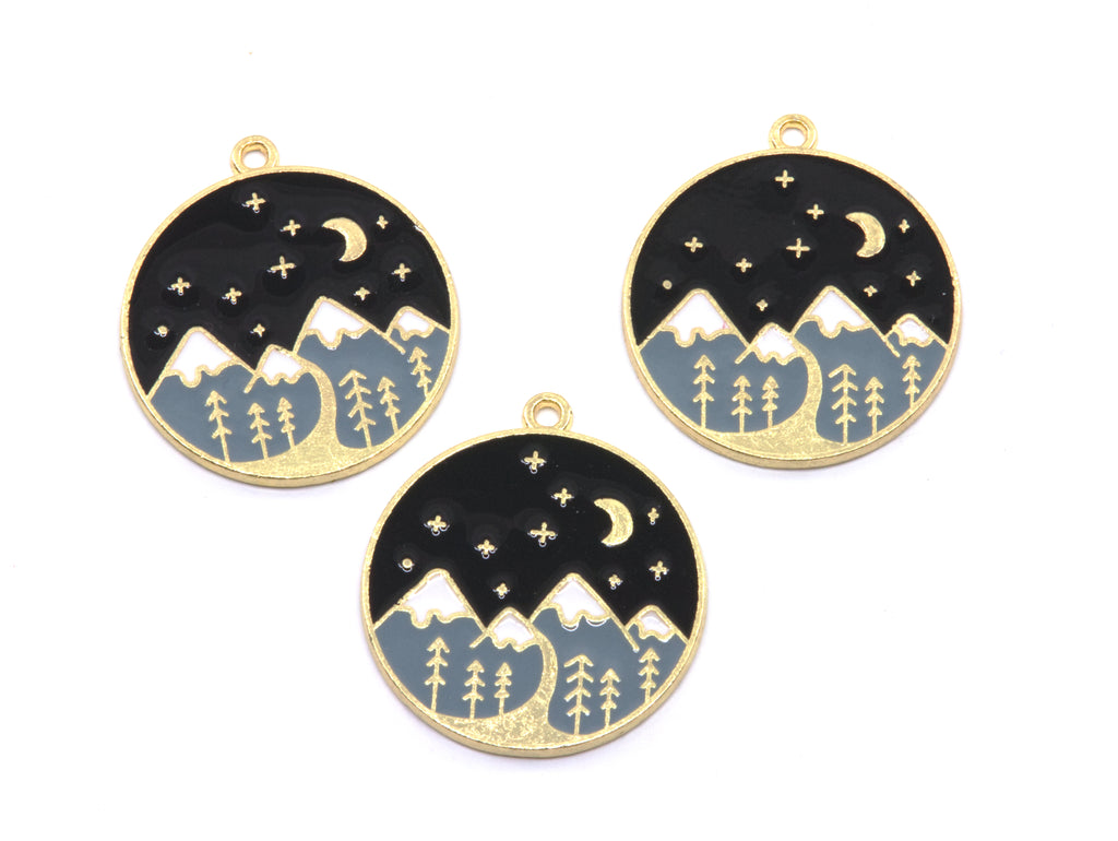 Three round gold-tone charms featuring a night sky and mountain landscape design, displayed on a clean white background.