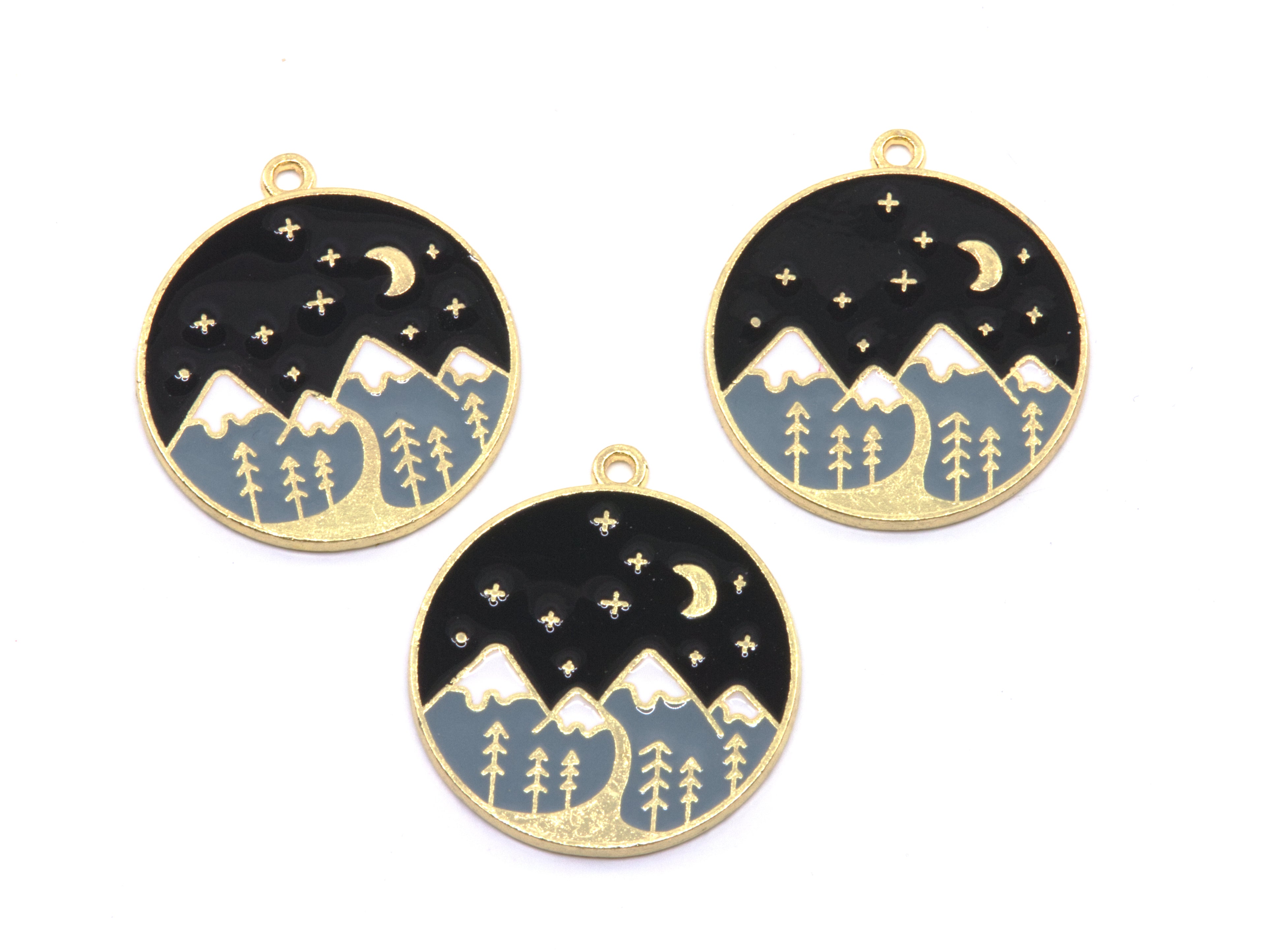 Three round gold-tone charms featuring a night sky and mountain landscape design, displayed on a clean white background.