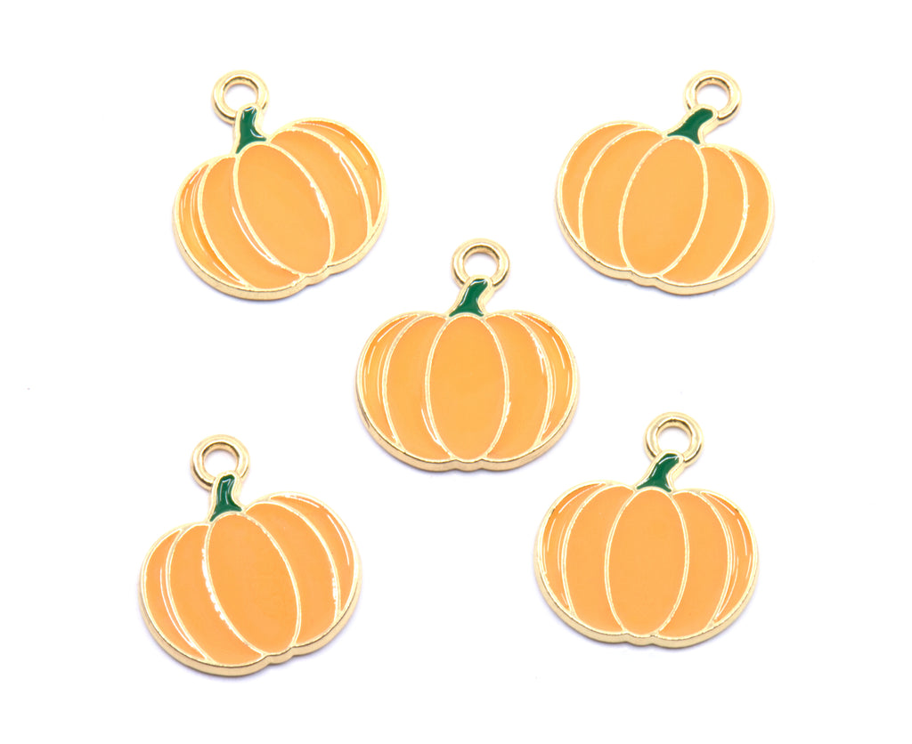 Five pumpkin-shaped charms with gold-tone metal borders and loops, featuring orange enamel bodies and small green stems, arranged on a plain white background.