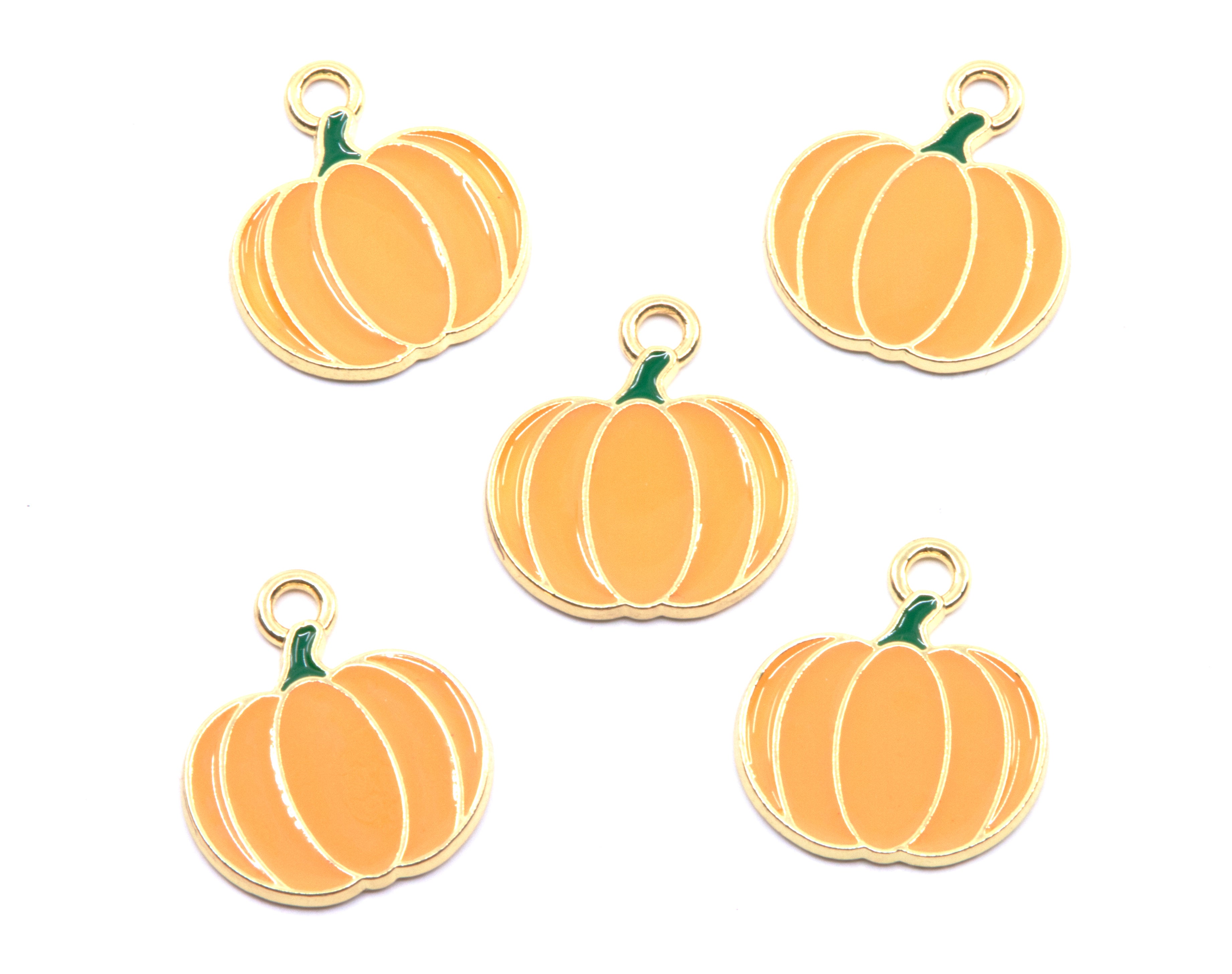 Five pumpkin-shaped charms with gold-tone metal borders and loops, featuring orange enamel bodies and small green stems, arranged on a plain white background.