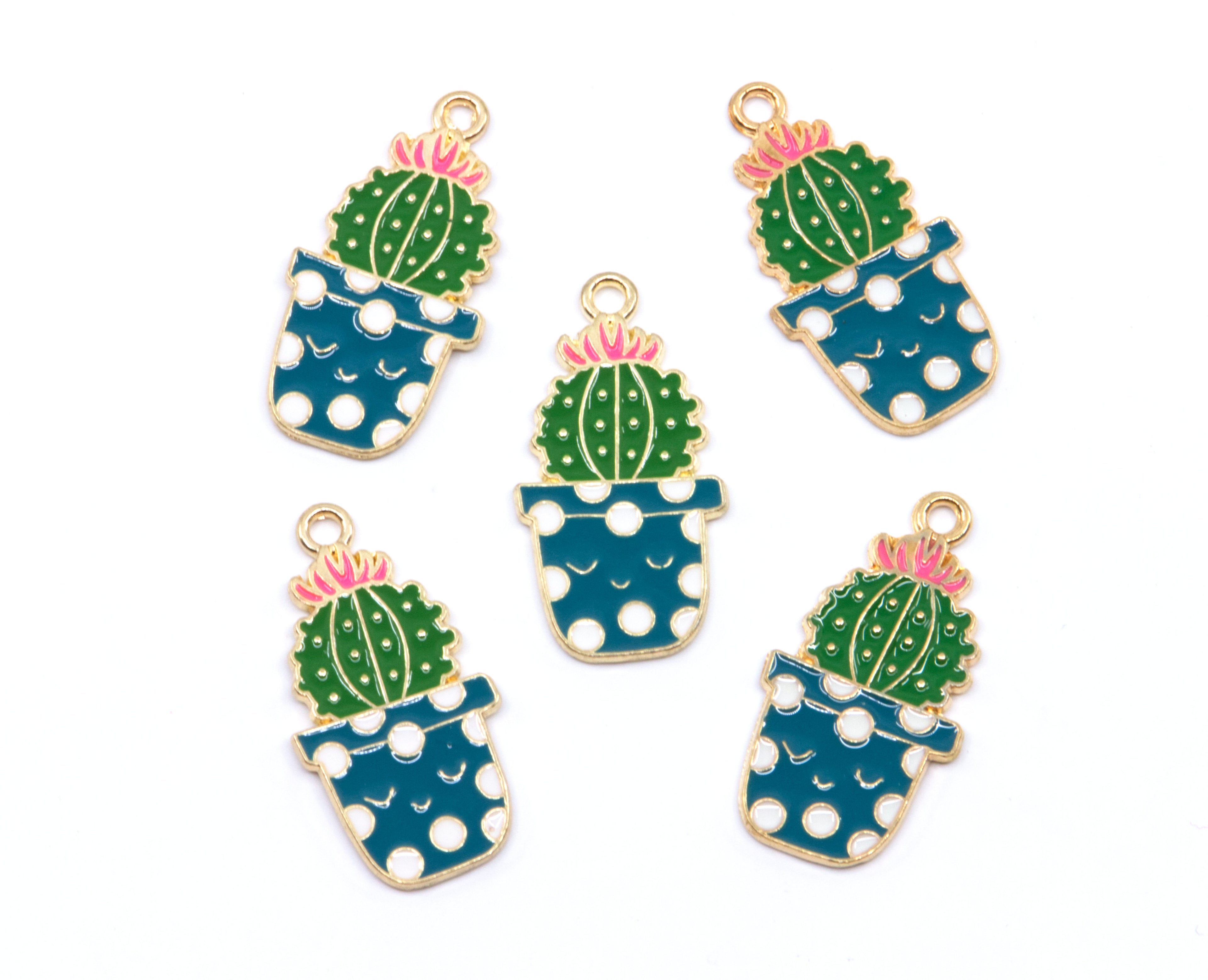 Five enamel jewelry charms shaped like potted cacti, arranged on a plain white background. Each charm features a green cactus with a pink flower, set in a blue pot with white polka dots and outlined in gold-tone metal.
