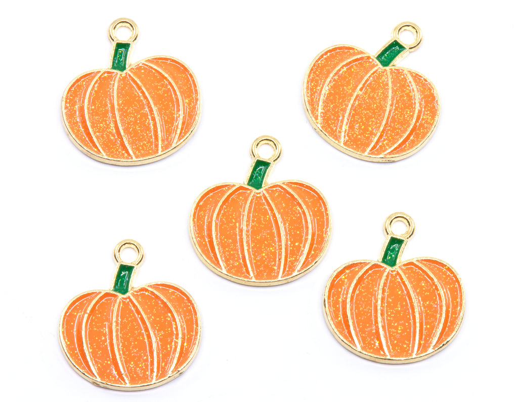 Five orange pumpkin-shaped charms with gold metal borders, white vertical stripes, and small green stems, arranged on a plain white background.