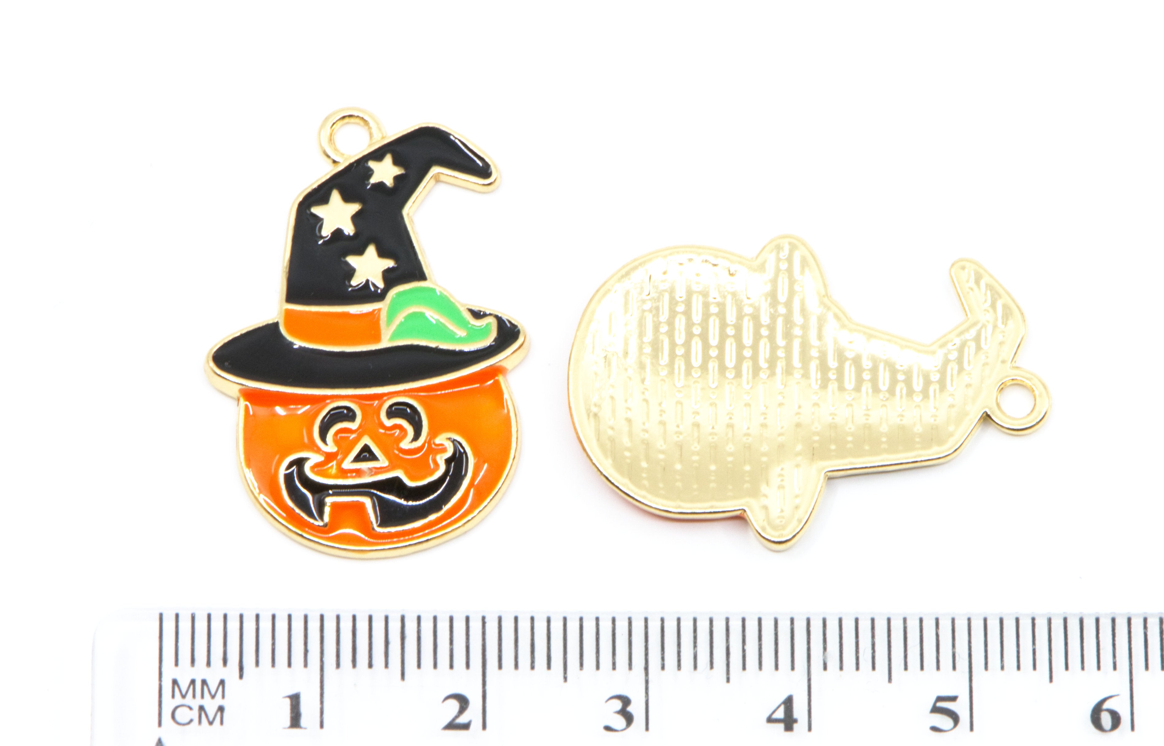 Two Halloween-themed metal charms shown on a white background with a ruler at the bottom for scale. 