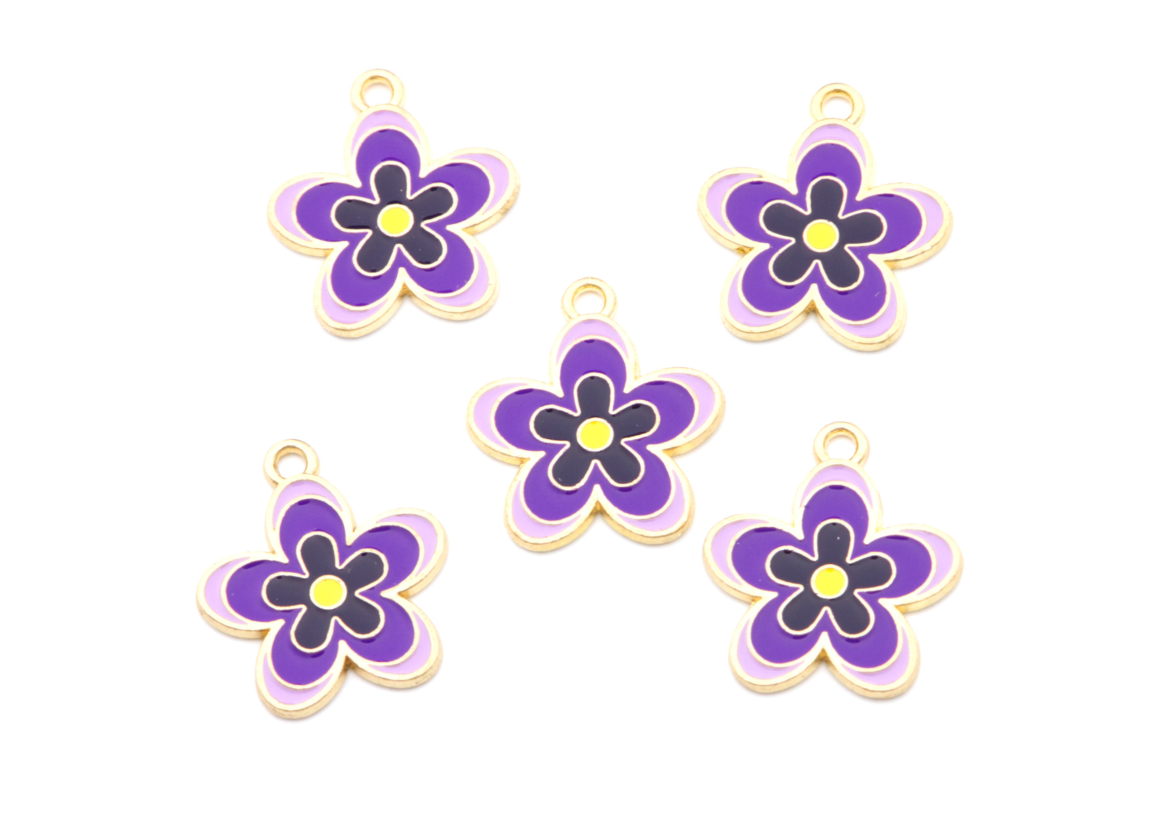 Five small flower-shaped jewelry charms with purple petals, yellow centers, and gold-tone edges, arranged on a plain white background.