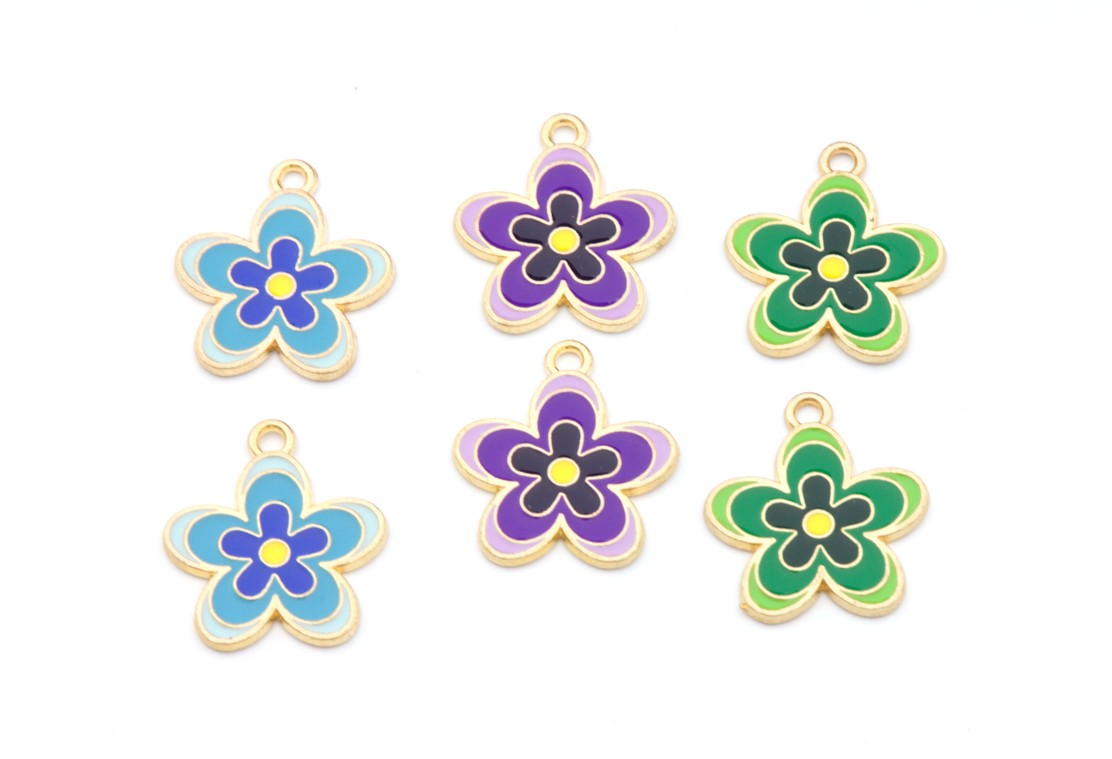 Six flower-shaped jewelry charms with gold-tone edges and enamel fills in blue, purple, and green, arranged on a plain white background.