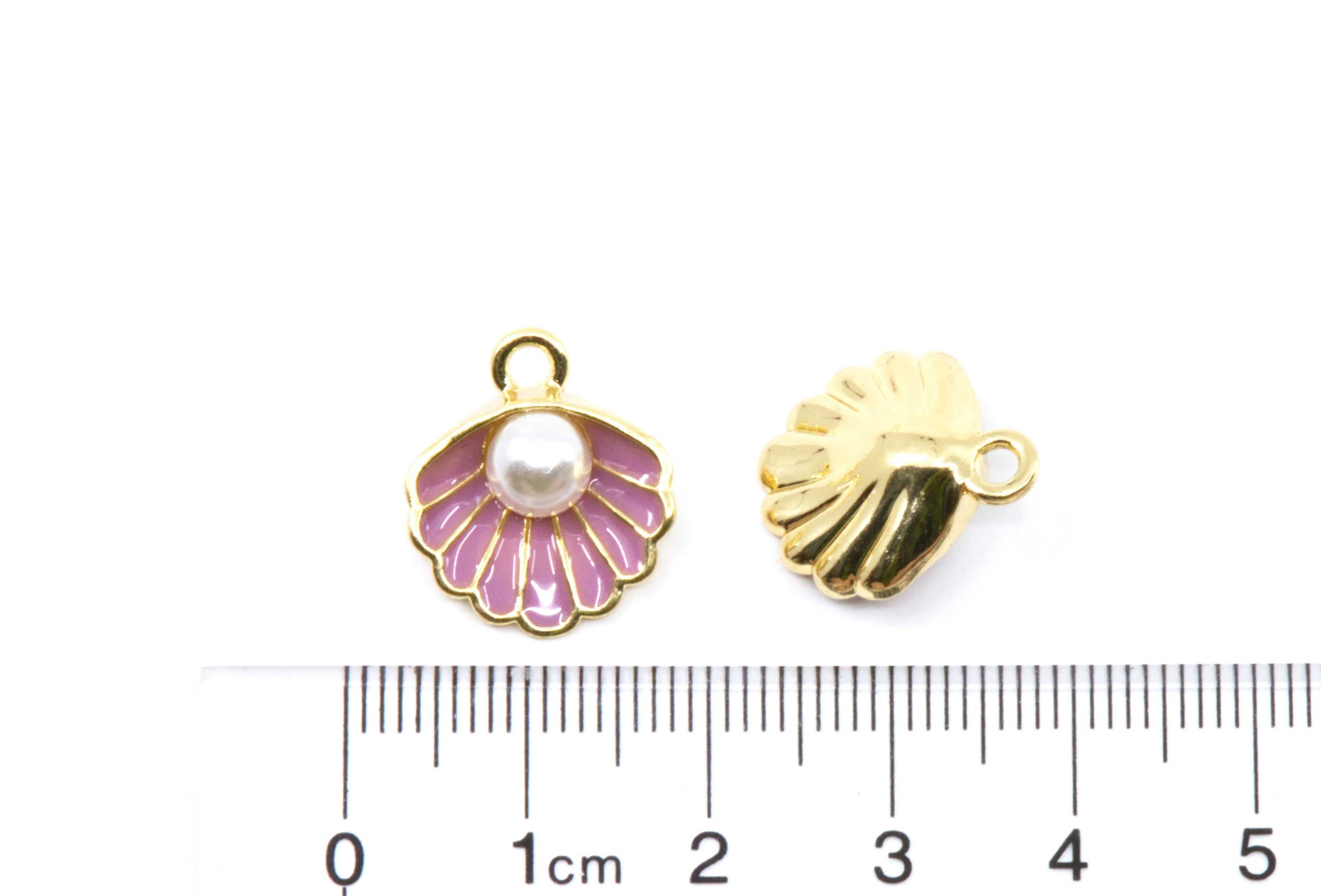 Two small shell-shaped jewelry charms shown on a white background with a cm ruler below for scale. 