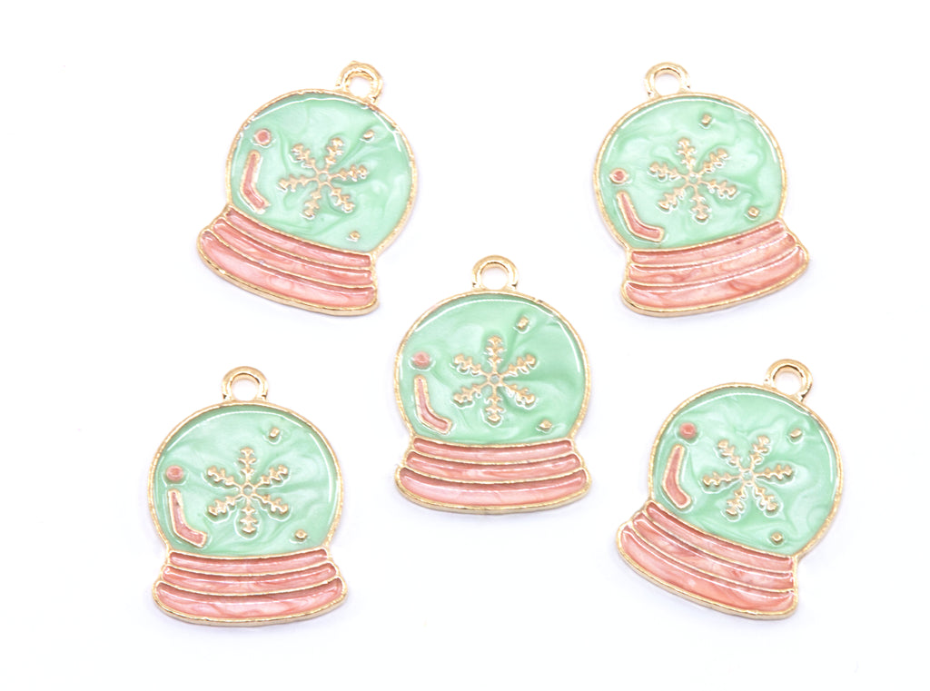 Five snow globe jewelry charms with light blue enamel, pink striped bases, and gold-tone metal borders on a white background.