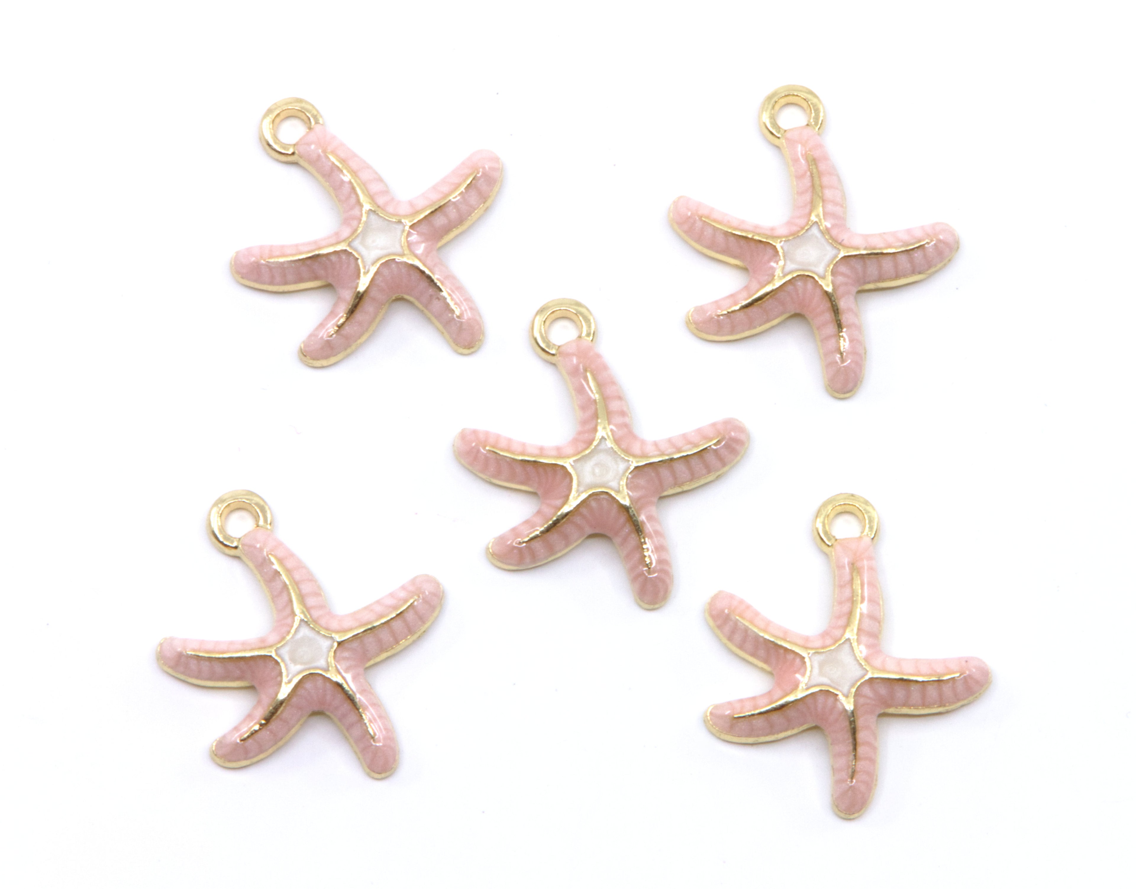 Five pink starfish charms with gold-tone metal outlines and loops, arranged on a plain white background.