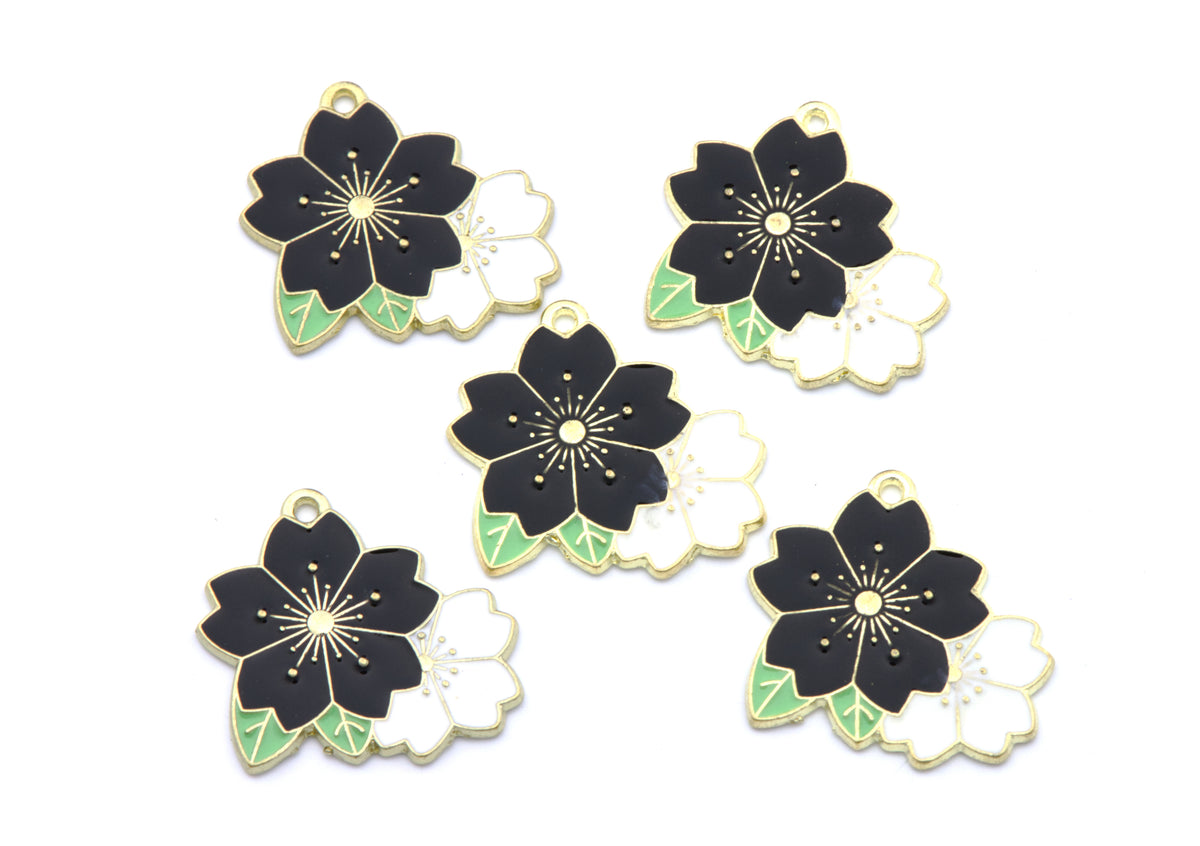 Five flower charms with black, white, and light green enamel details, arranged on a plain white background