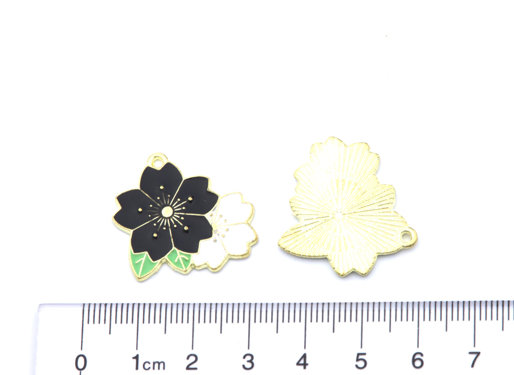 two black and white flower charms white background with a cm ruler for scale. 