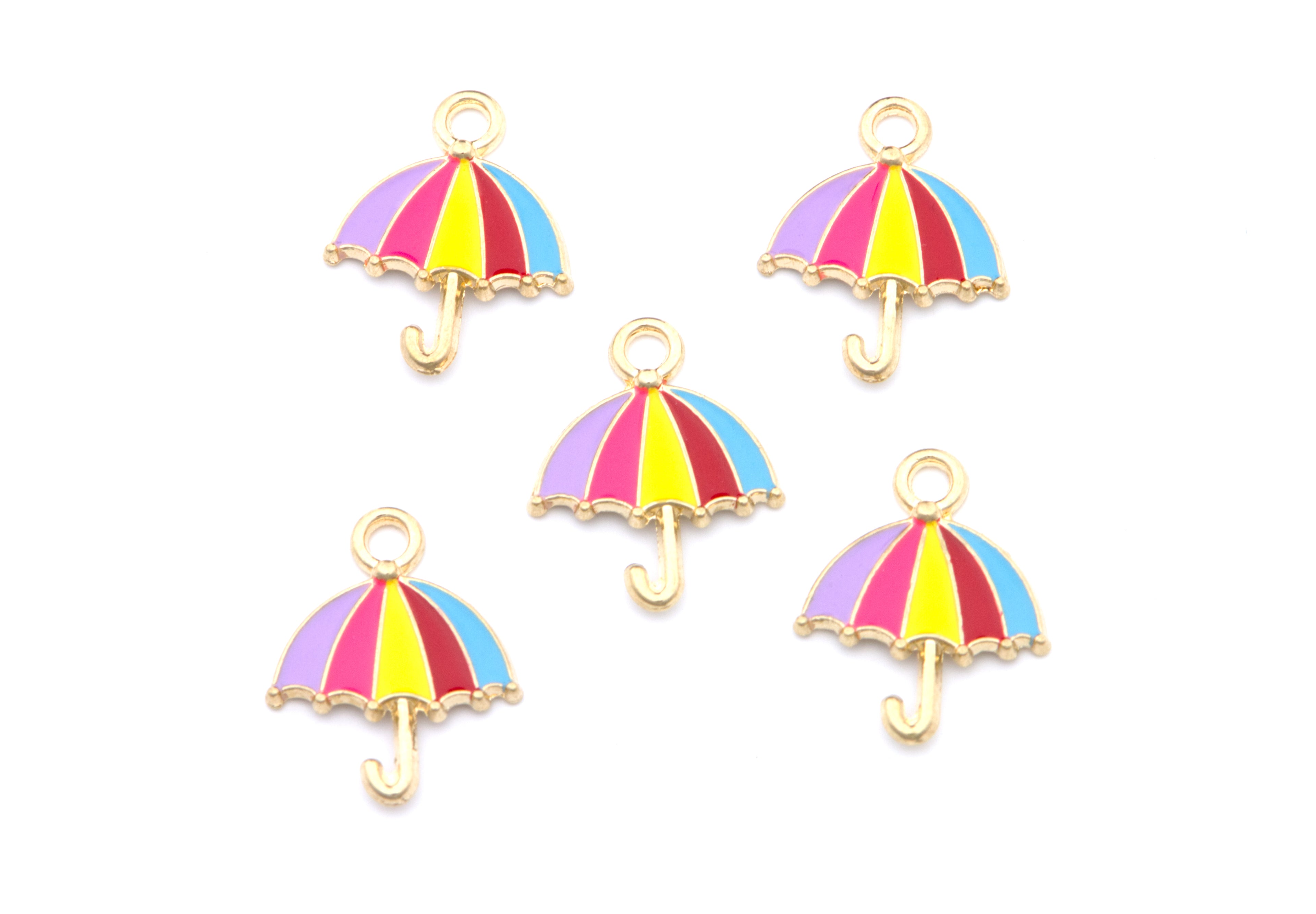 Five small umbrella-shaped jewelry charms with gold-tone metal outlines and colorful enamel stripes in pink, purple, yellow, and blue, arranged on a plain white background.