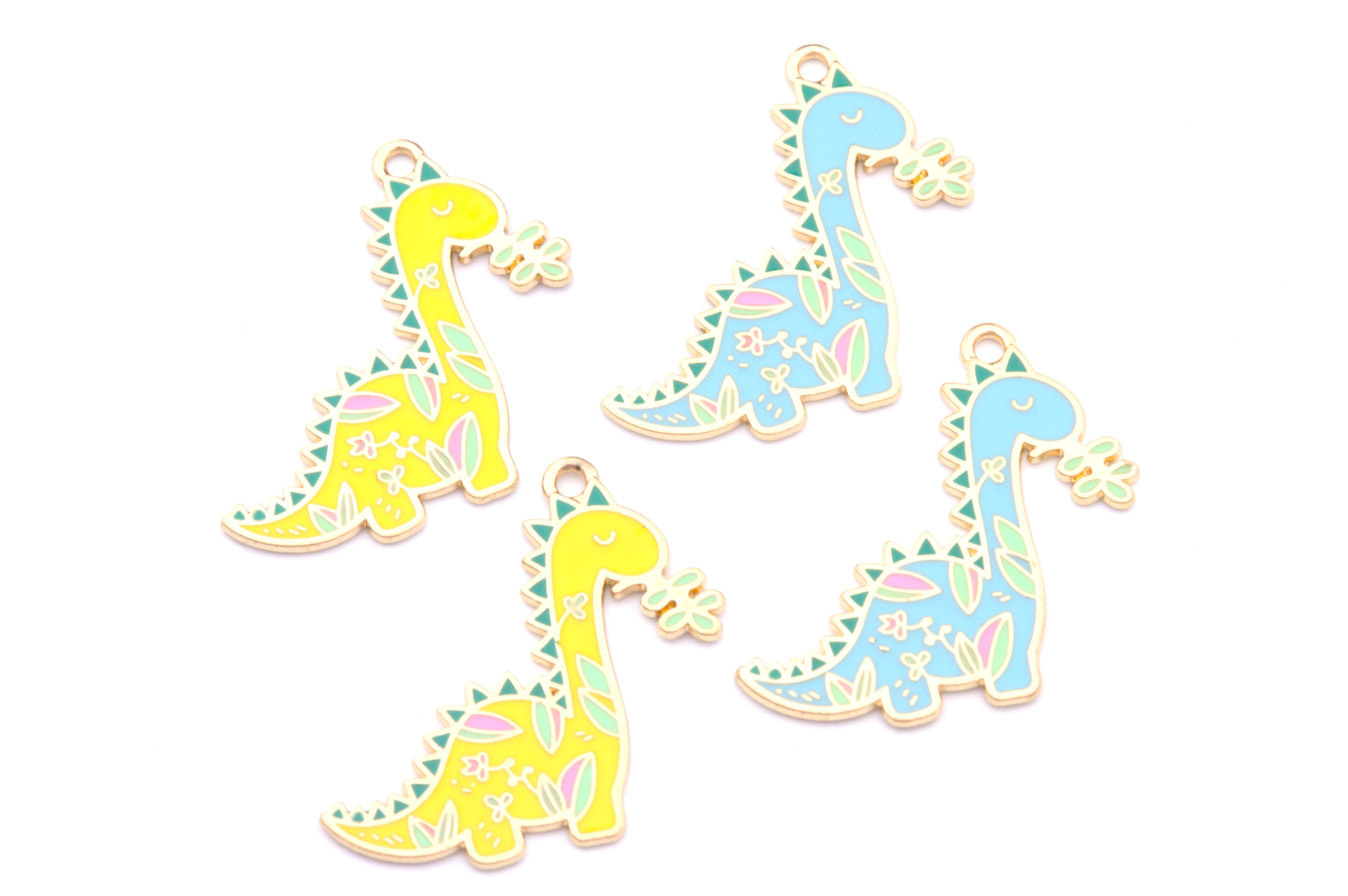 Four enamel dinosaur charms on a white background, featuring two yellow and two light blue dinosaurs decorated with green, pink, and white floral patterns.