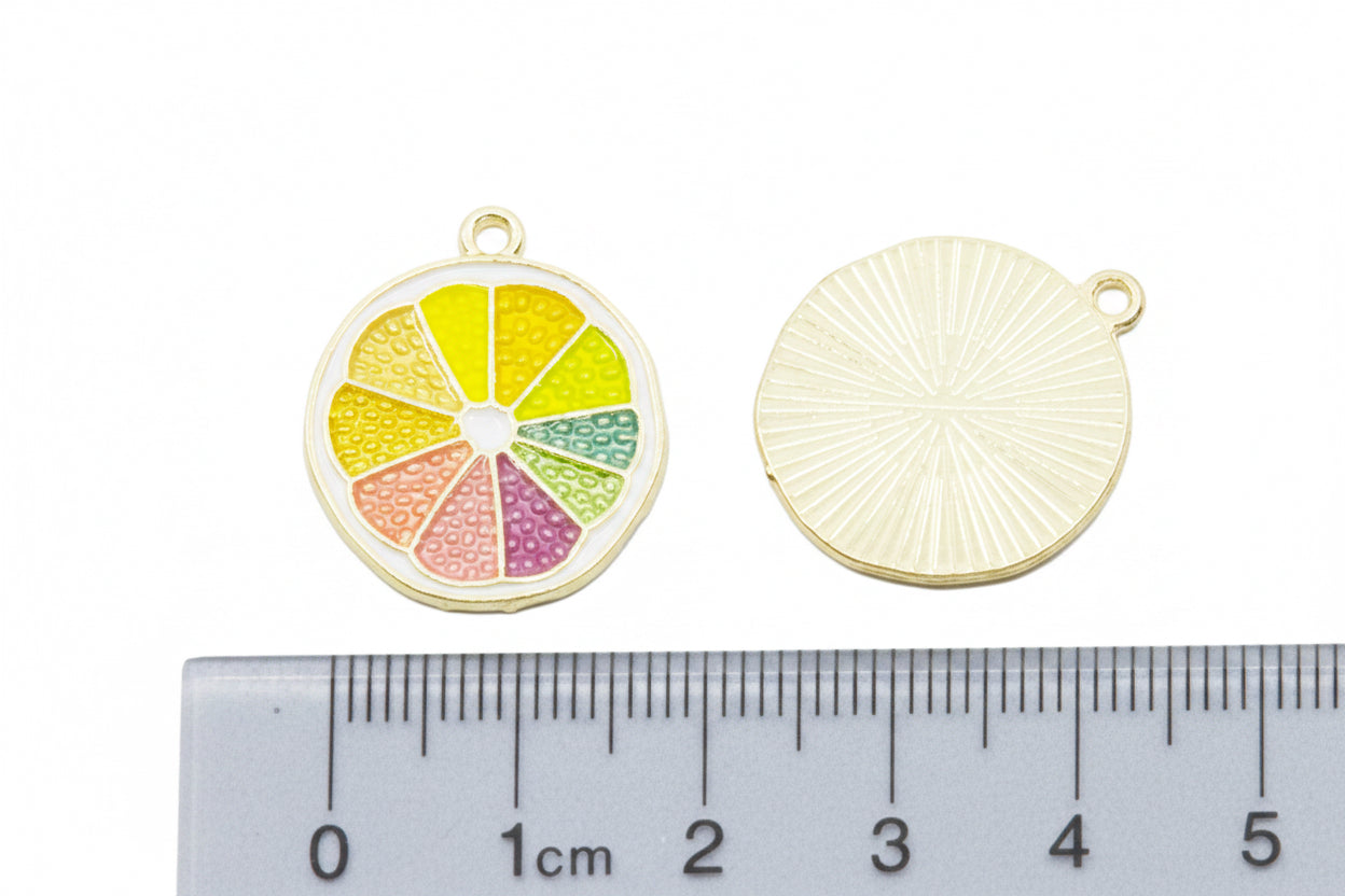 Two citrus fruit enamel charms above a cm ruler below for scale on a white background 