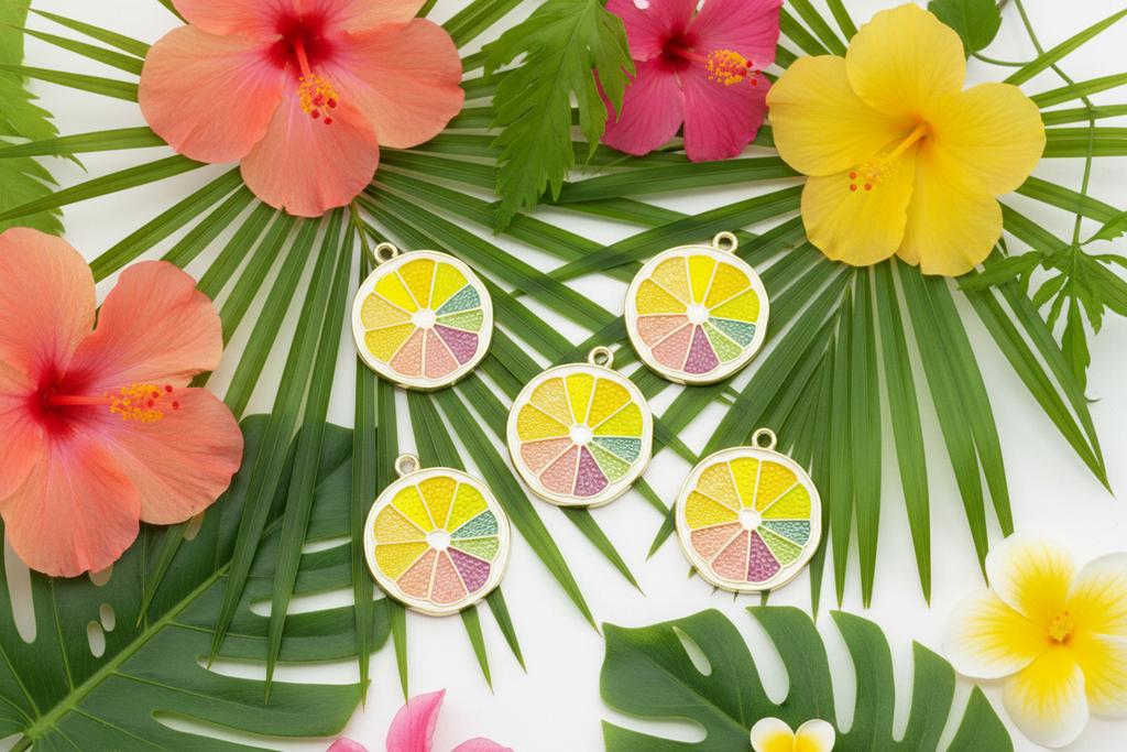 Five round pendant charms designed like citrus slices with pastel yellow, green, pink, and orange segments on a white background, styled with tropical hibiscus flowers and palm leaves.