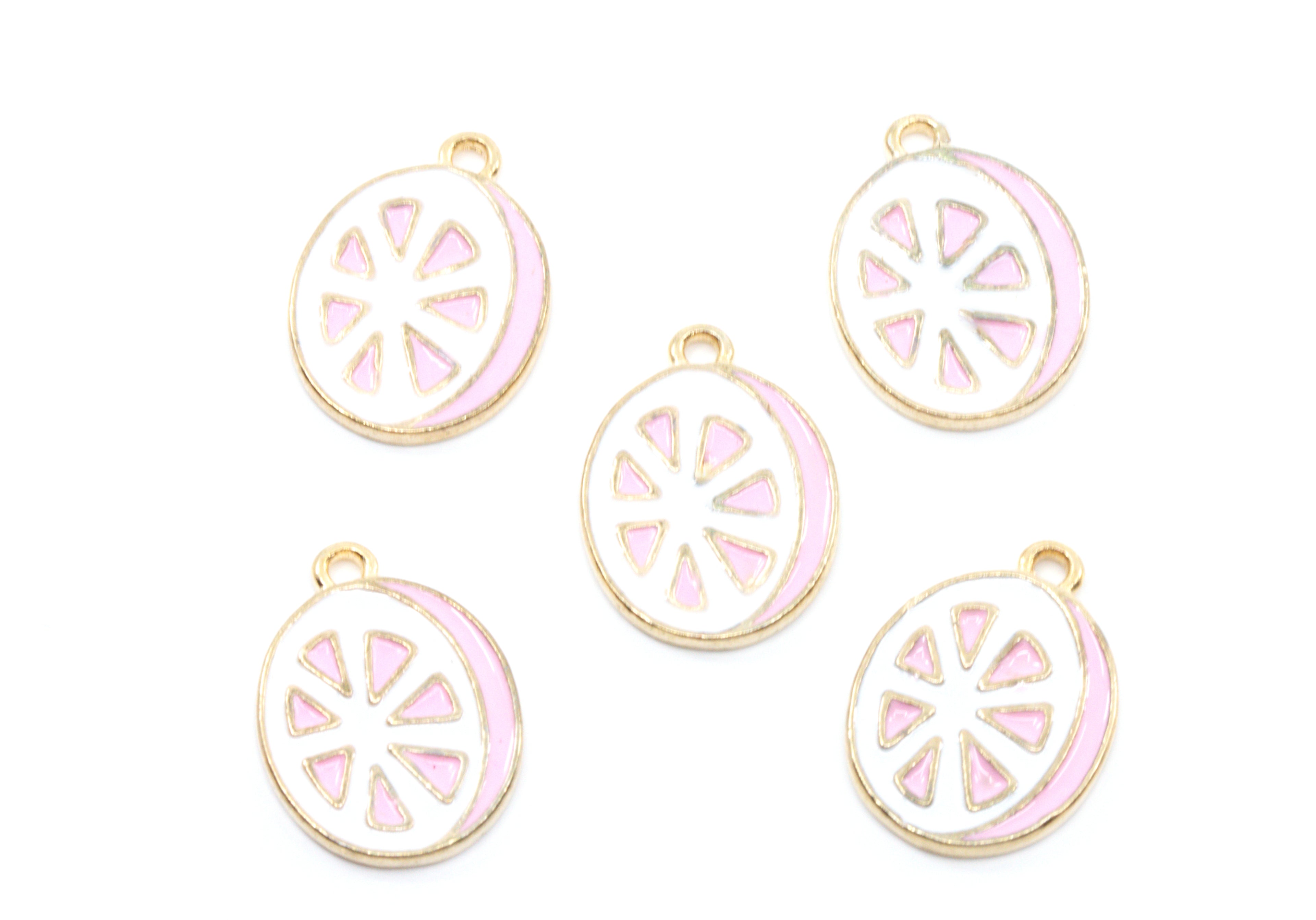 Five round enamel charms shaped like sliced  grapefruit, featuring a white center with pink segments and a gold-tone border, arranged on a plain white background.