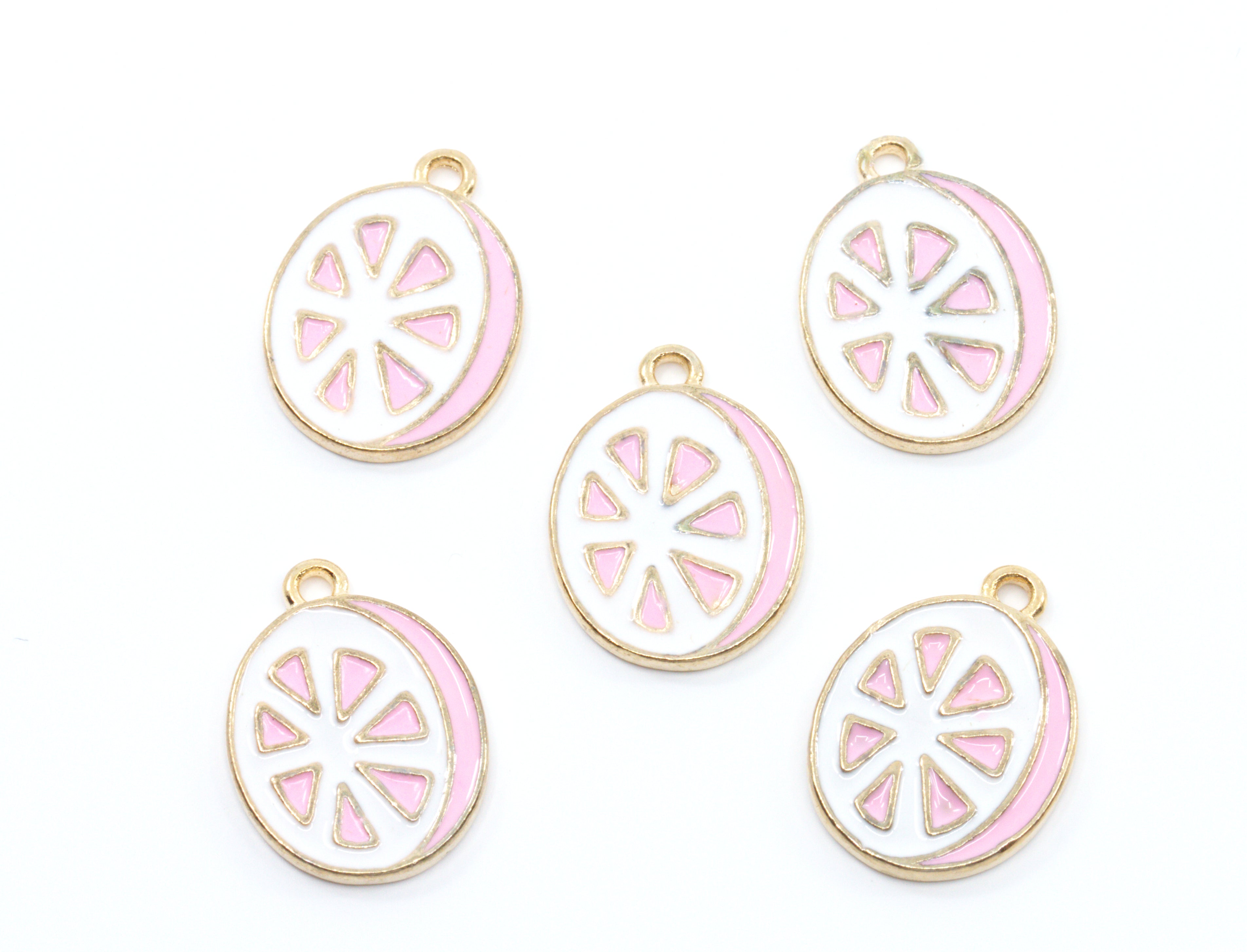 Five round enamel charms shaped like sliced  grapefruit, featuring a white center with pink segments and a gold-tone border, arranged on a plain white background.