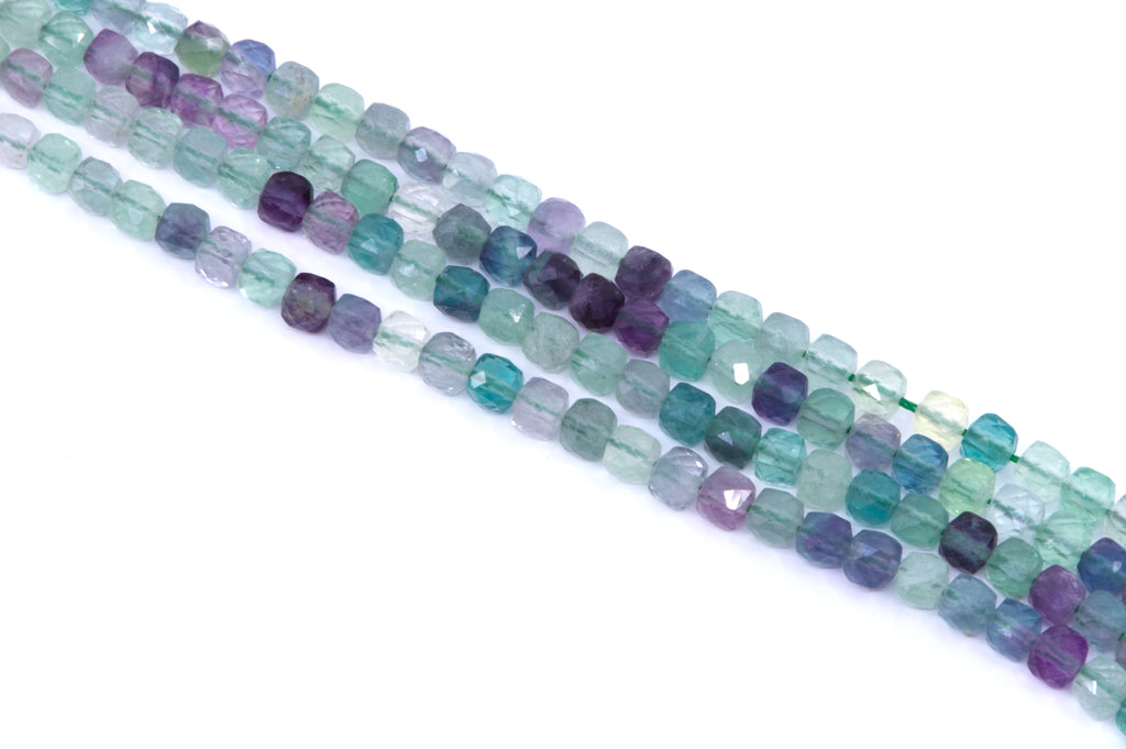 Four strands of faceted gemstone green fluorite beads in shades of teal, green, blue, and purple, arranged diagonally on a white background.