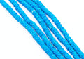 Multiple strands of bright blue polymer clay hexagon disc beads, arranged diagonally on a plain white background.