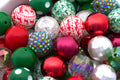 A close-up pile of colorful Christmas bubblegum beads, including shiny red, green, and white patterned, some iridescent glittery and faceted white beads