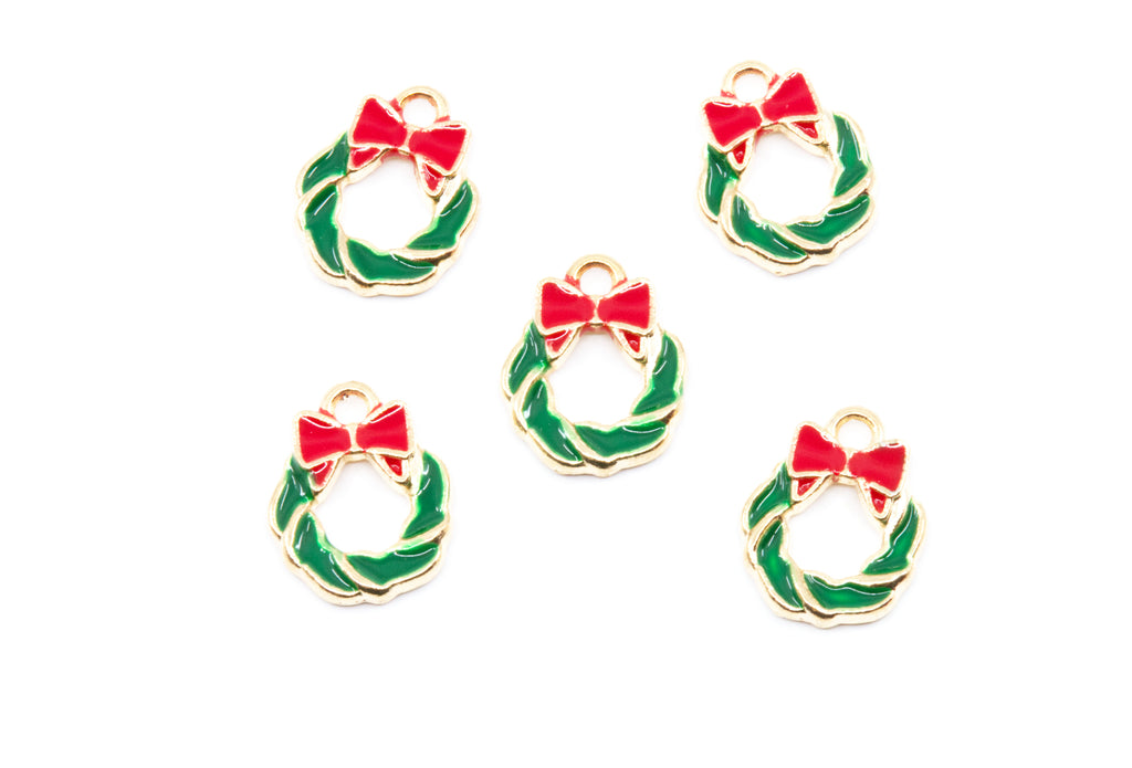 Five small holiday wreath charms with gold-tone metal edges, green enamel fill, and red bow details, arranged on a plain white background.