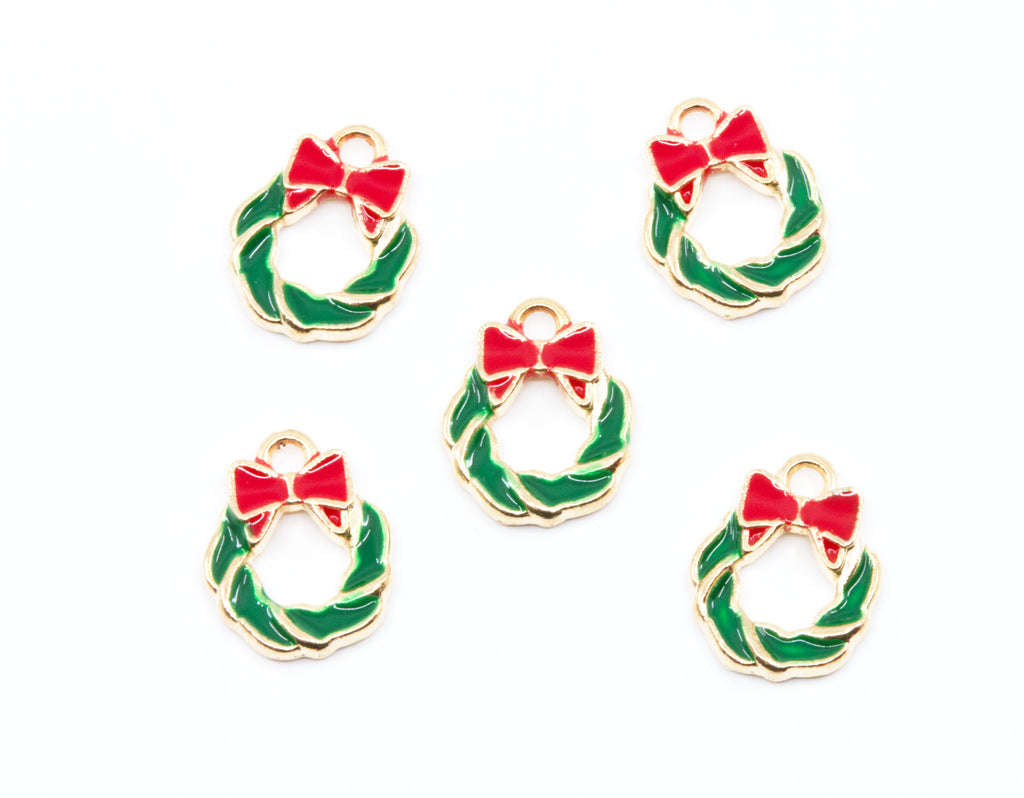 Five small holiday wreath charms with gold-tone metal edges, green enamel fill, and red bow details, arranged on a plain white background.
