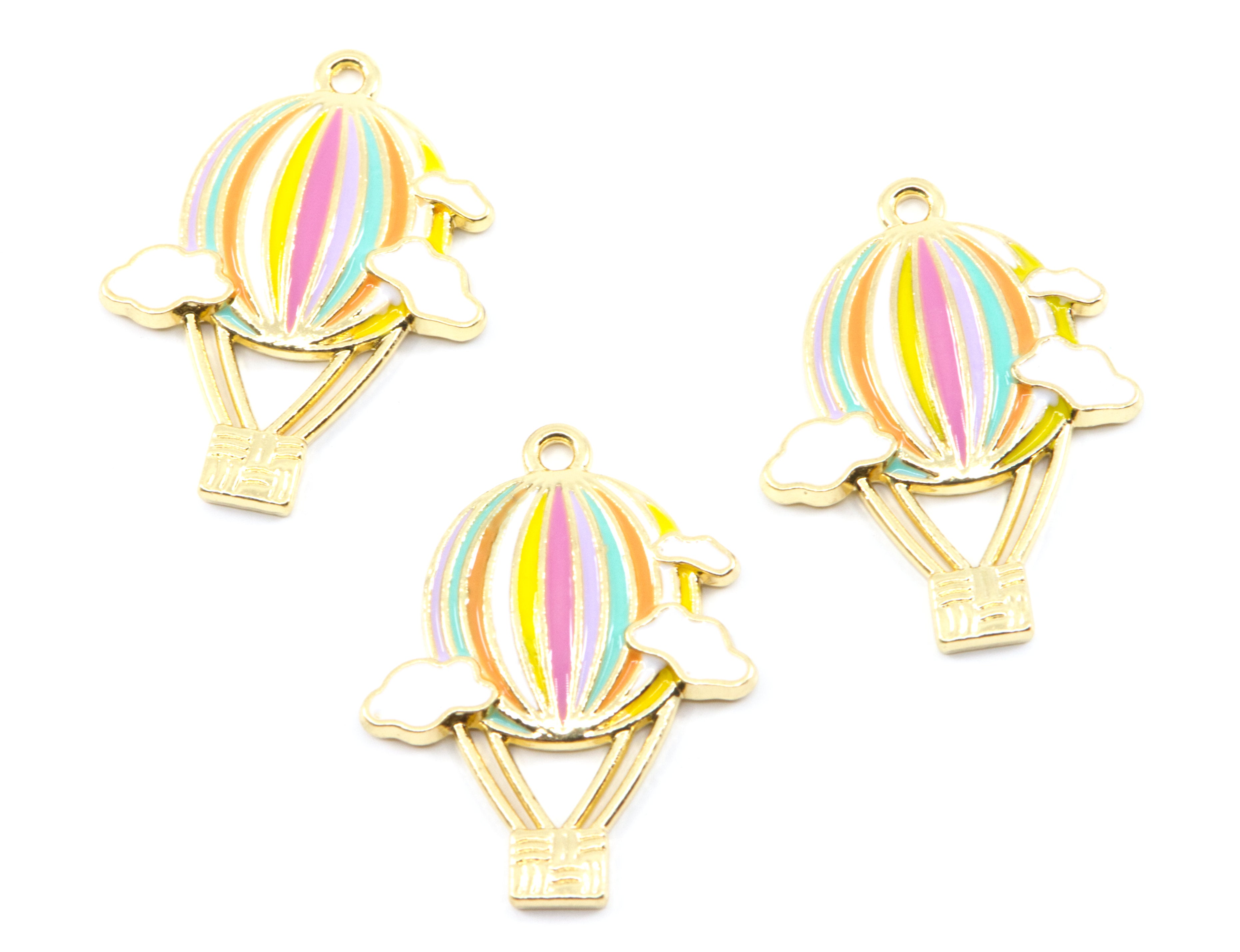 Three gold-plated hot air balloon charms with pastel rainbow stripes and small clouds, arranged on a plain white background.
