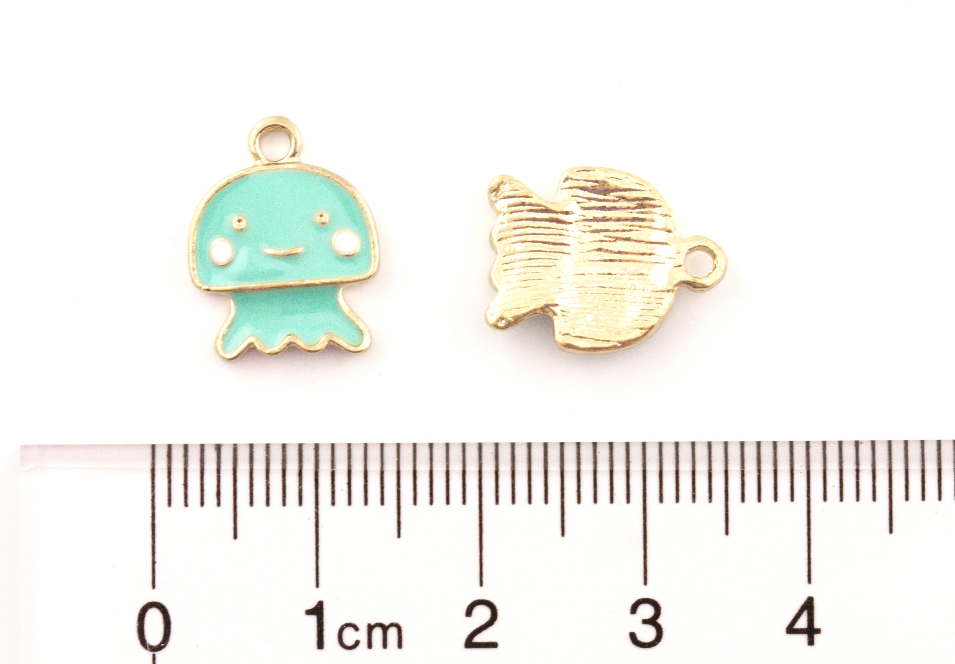 Two small jewelry charms shown above a ruler for scale: a mint green jellyfish charm on the left and the charm's backside on the right, on a white background.
