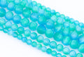 Multiple strands of round turquoise-blue dyed gypsum selenite beads arranged diagonally on a clean white background.