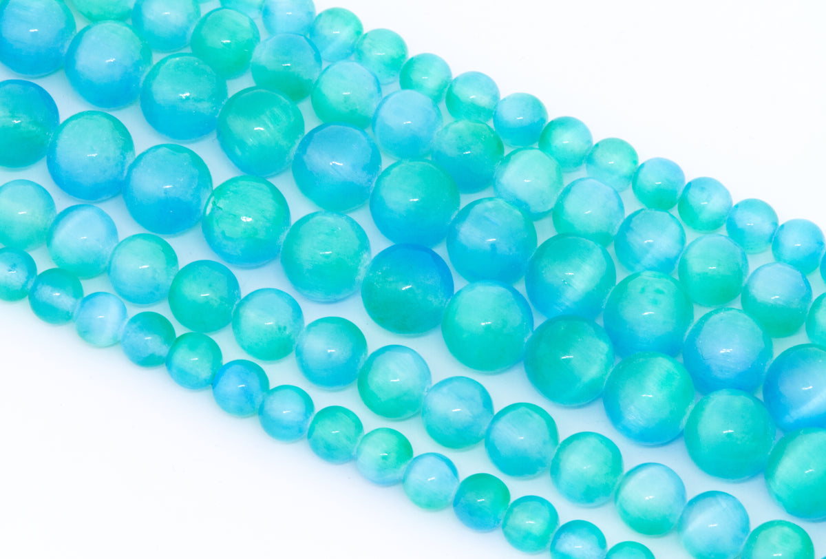 Multiple strands of round turquoise-blue dyed gypsum selenite beads arranged diagonally on a clean white background.