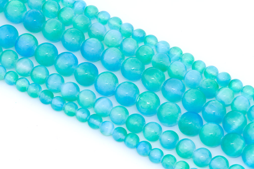 Multiple strands of round turquoise-blue dyed gypsum selenite beads arranged diagonally on a clean white background.