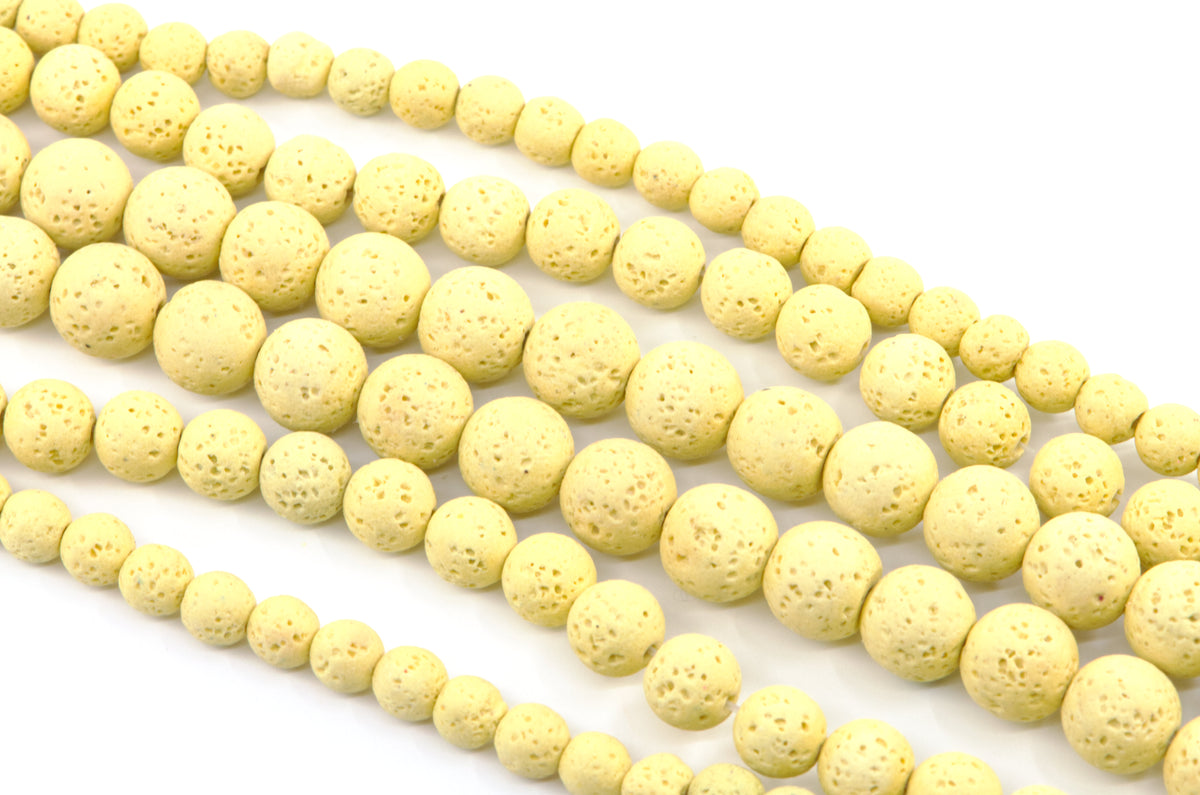 Multiple strands of pale yellow porous lava stone beads arranged diagonally on a clean white background.