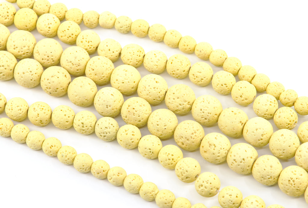 Multiple strands of pale yellow porous lava stone beads arranged diagonally on a clean white background.