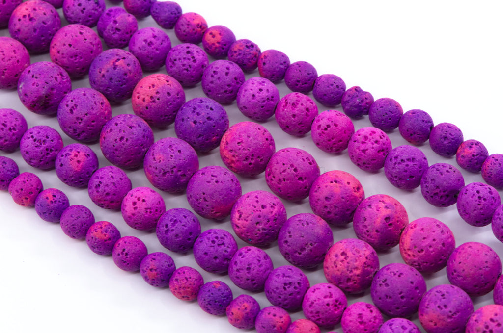 Multiple strands of porous lava stone beads in vibrant shades of purple and pink, arranged diagonally on a clean white background.
