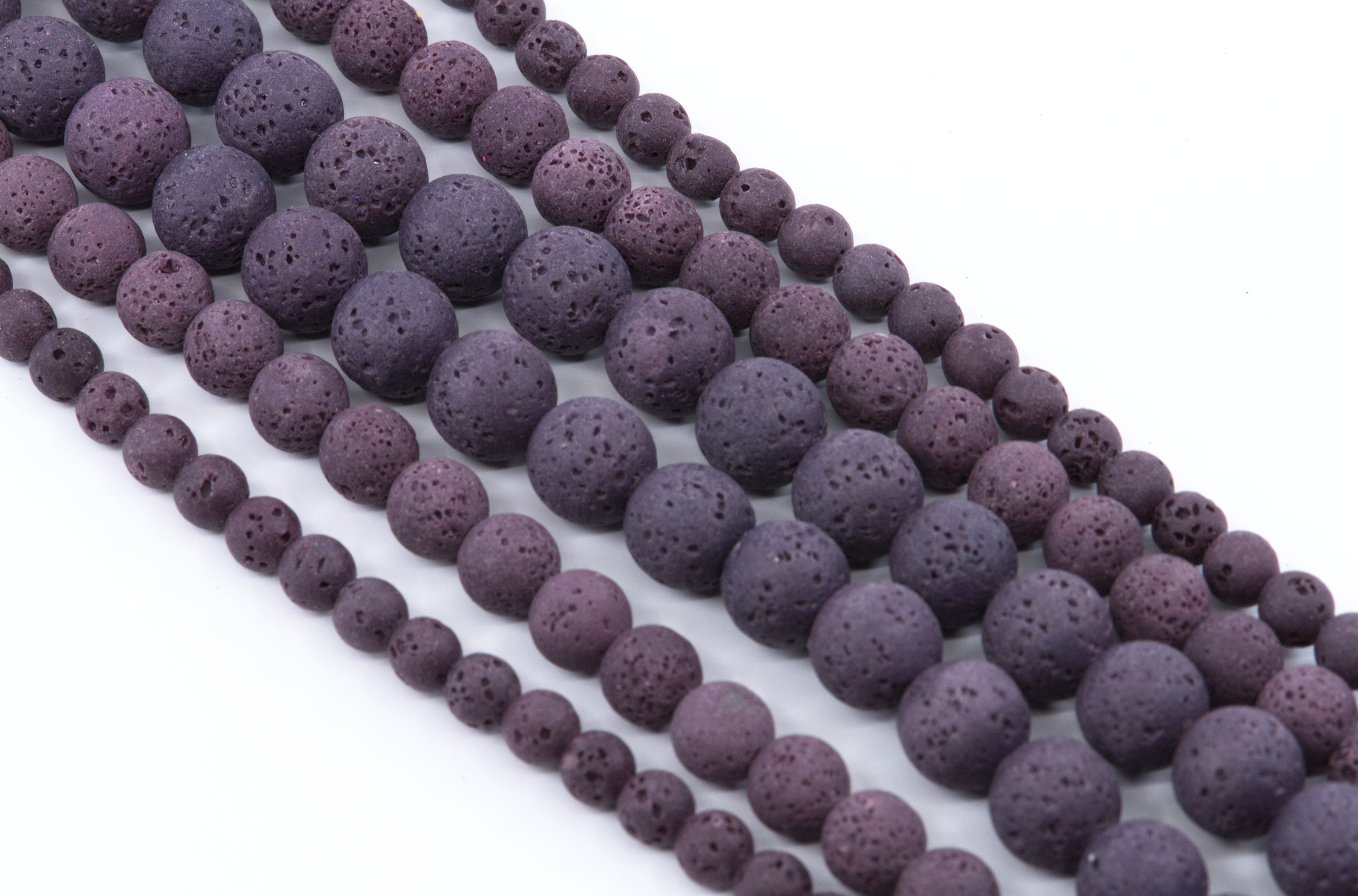 Multiple strands of porous purple lava stone beads in varying sizes, displayed diagonally on a clean white background.
