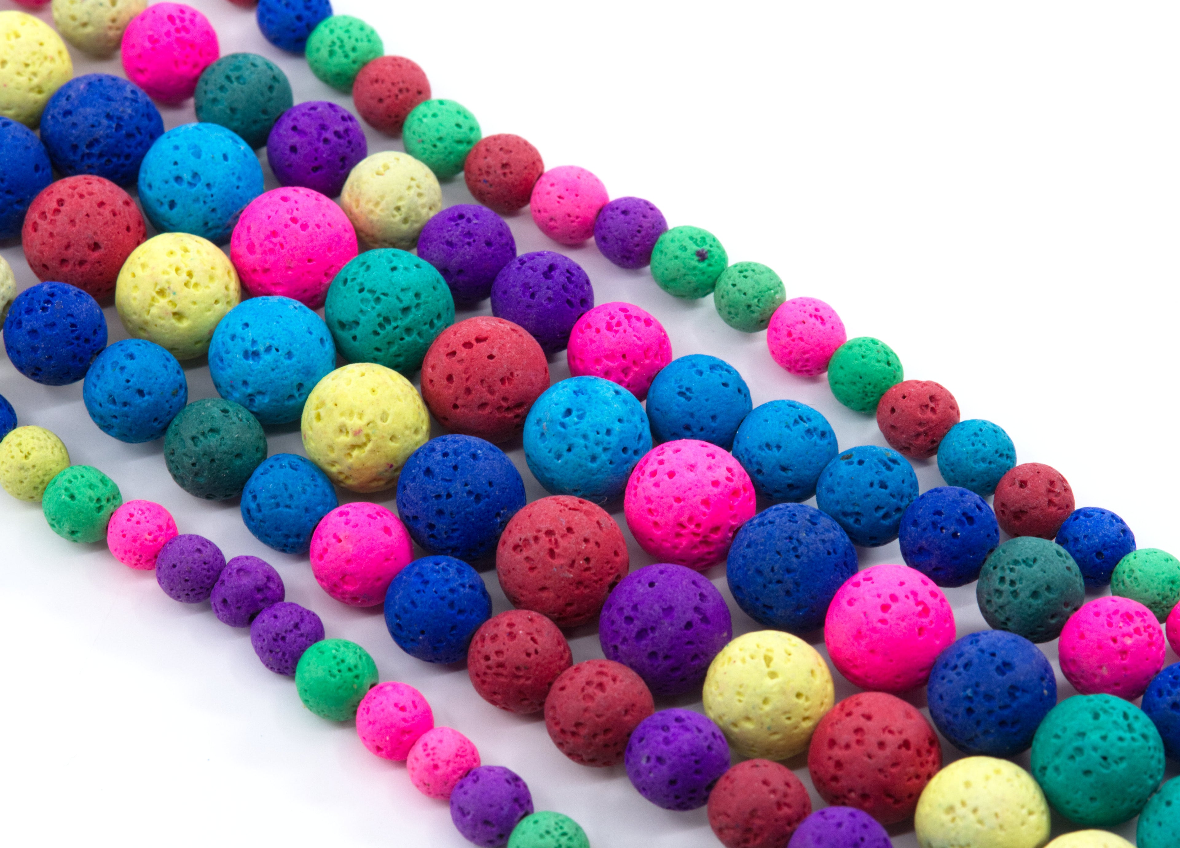 Multiple strands of porous lava stone beads in a rainbow of colors, including blue, pink, purple, green, yellow, and red, arranged diagonally on a white background.