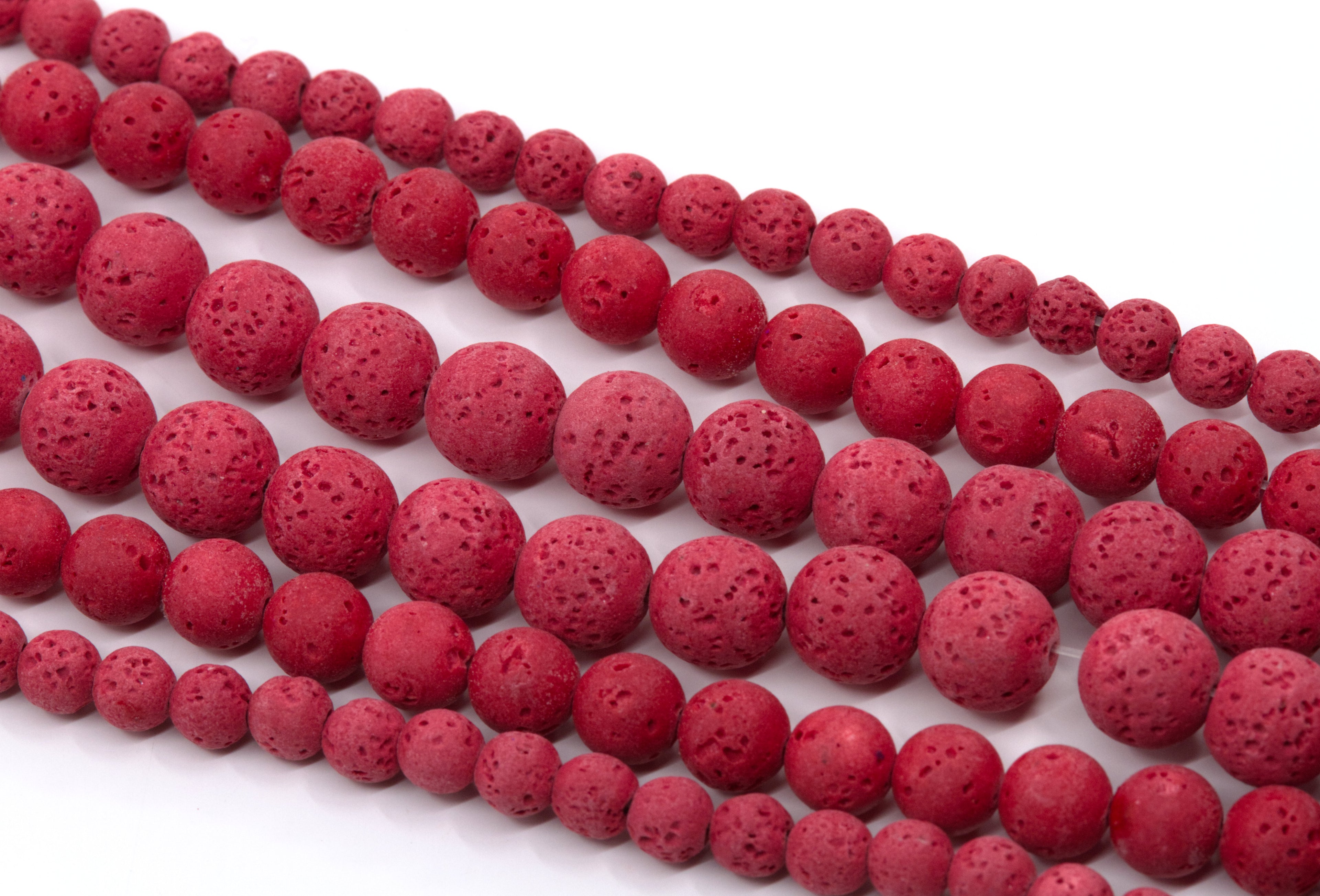 Red porous lava stone beads strung on strands, arranged diagonally on a white background.