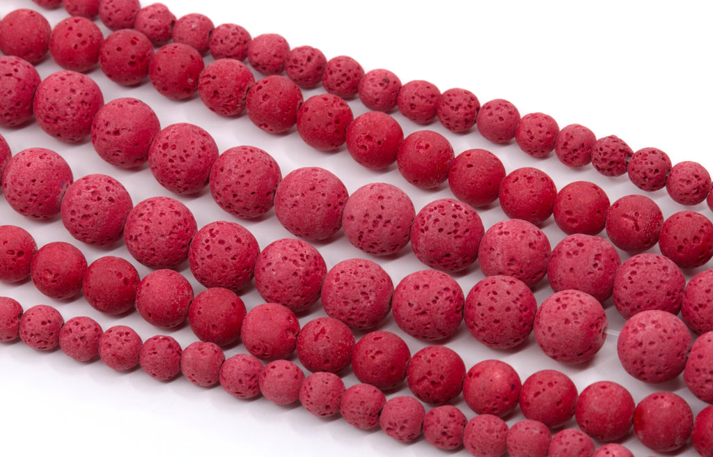 Red porous lava stone beads strung on strands, arranged diagonally on a white background.