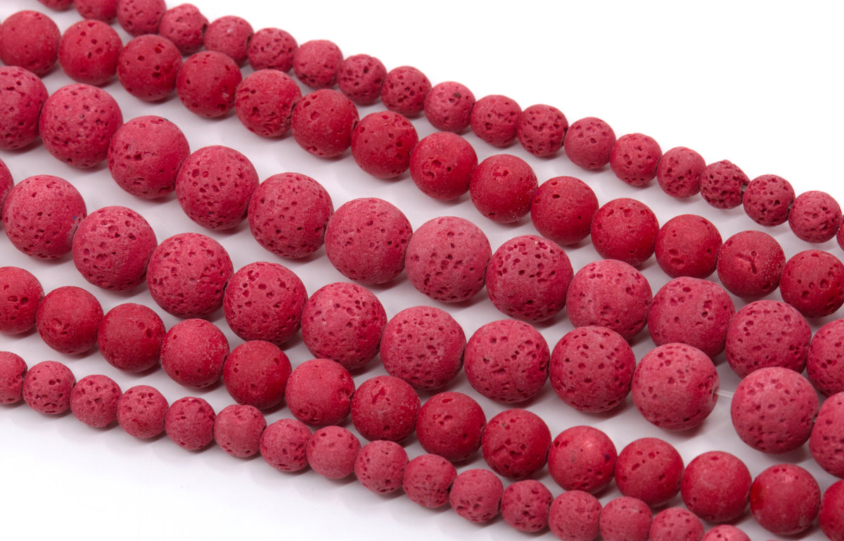 Red porous lava stone beads strung on strands, arranged diagonally on a white background.