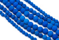 Multiple strands of textured blue lava stone beads arranged diagonally on a clean white background.