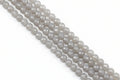 Faceted round agate beads in pale gray  arranged in diagonal rows on a light gray background.