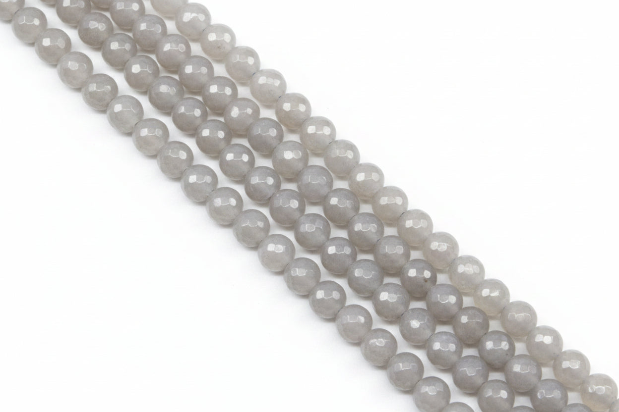 Faceted round agate beads in pale gray  arranged in diagonal rows on a light gray background.